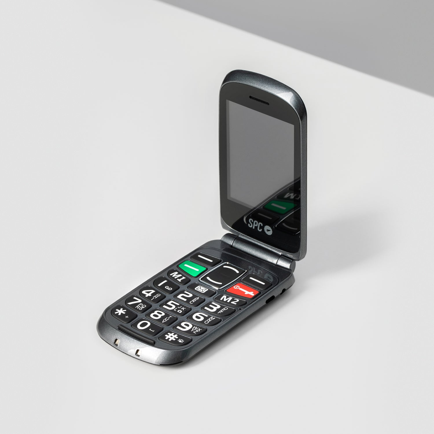 Teléfono plegable gris abierto, mostrando la pantalla y el teclado.