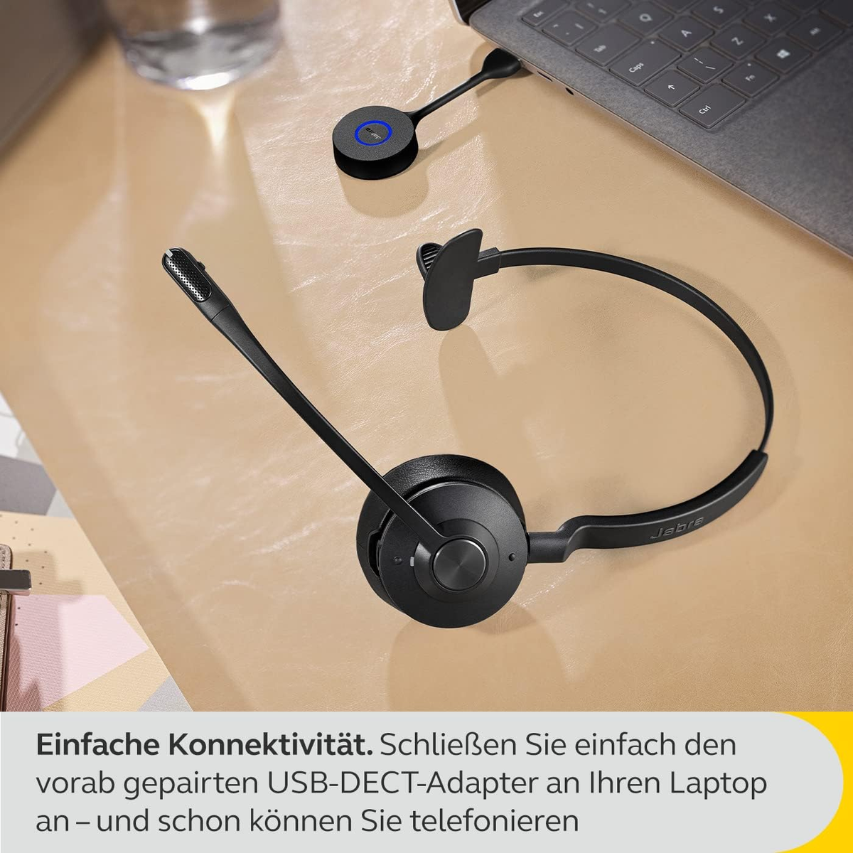 Schwarzes Jabra-Headset und USB-DECT-Adapter auf einem Schreibtisch. Text auf Deutsch. Der Hintergrund ist beige.