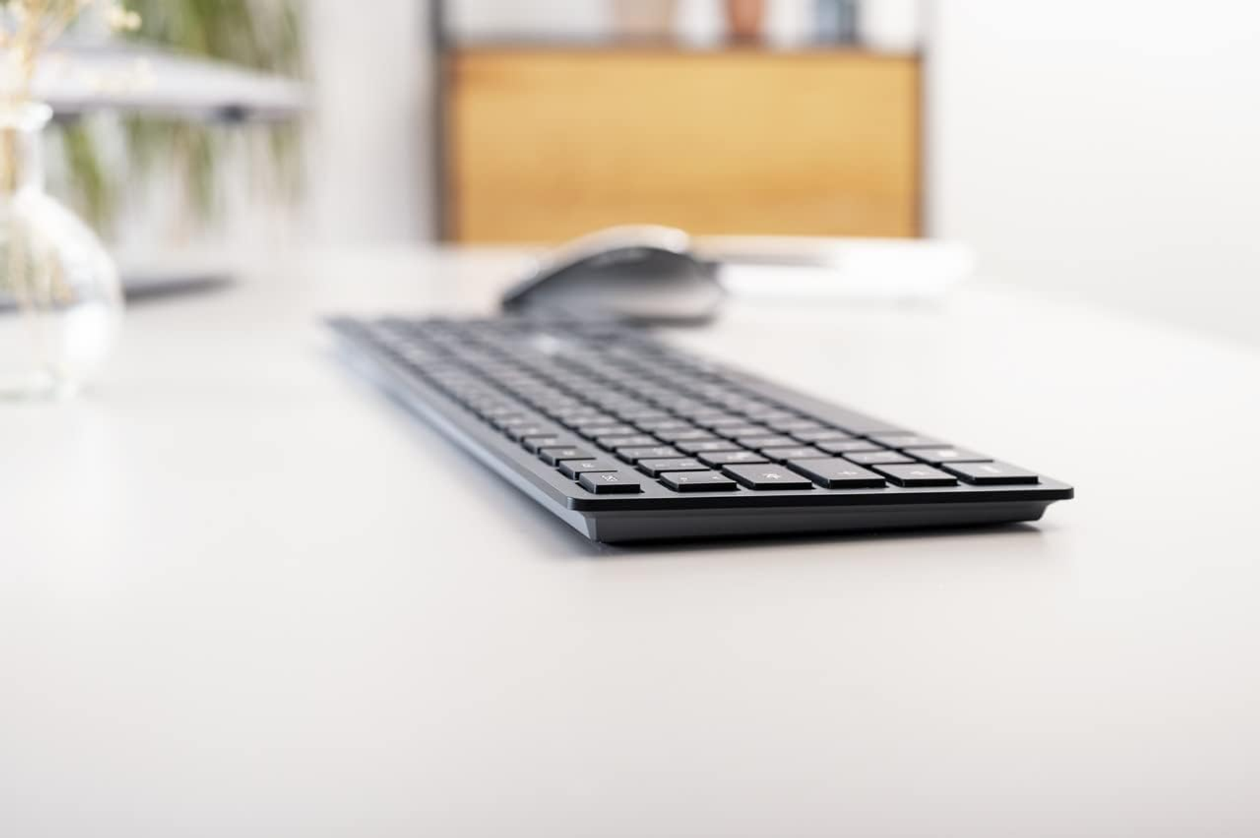 Schwarze Tastatur auf weißem Schreibtisch, Seitenansicht.