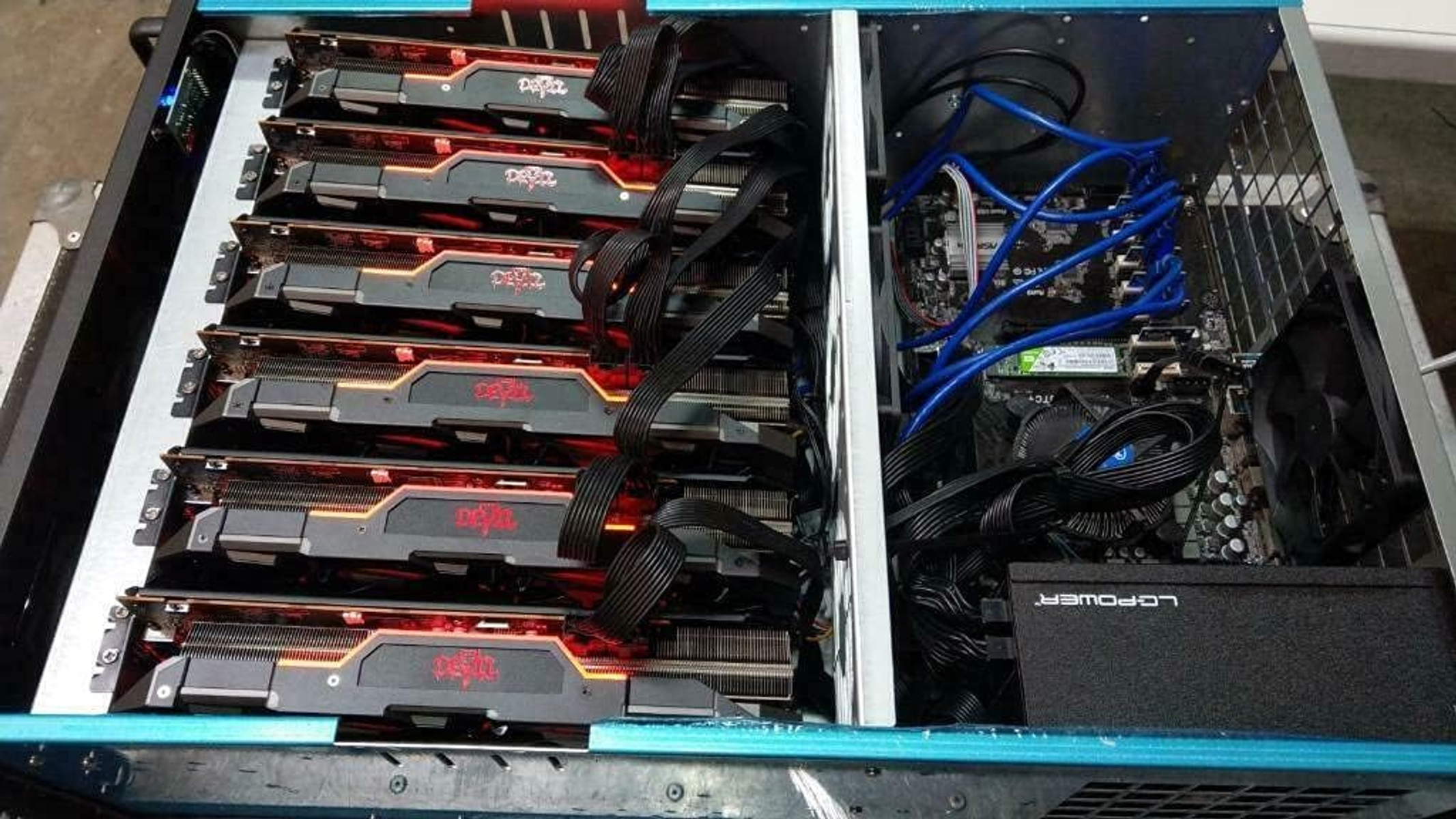 Otwarta obudowa komputera z wieloma kartami graficznymi i widocznymi komponentami.