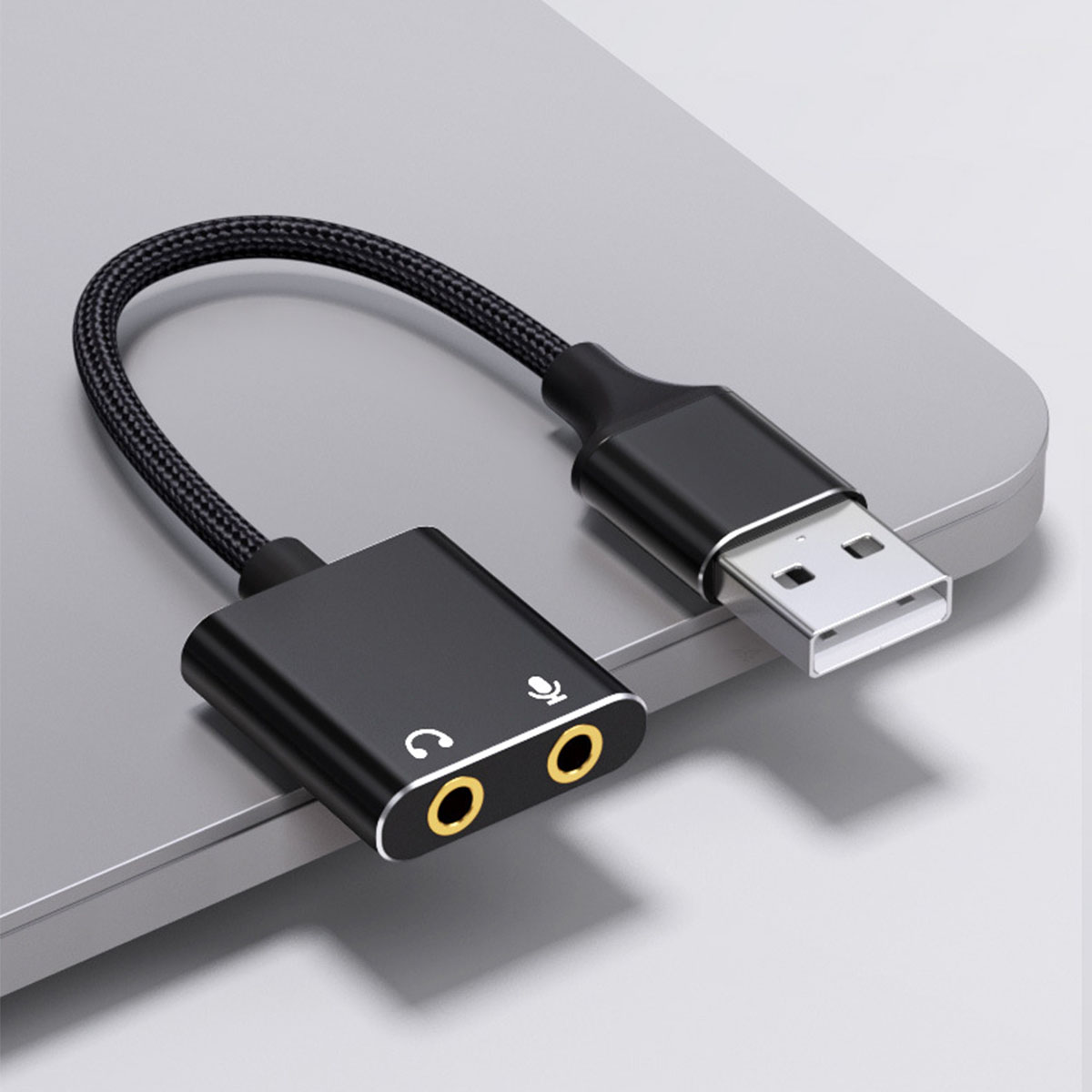 Schwarzer USB-Adapter mit USB-A-Anschluss und zwei Audiobuchsen, verbunden durch ein schwarzes Kabel.