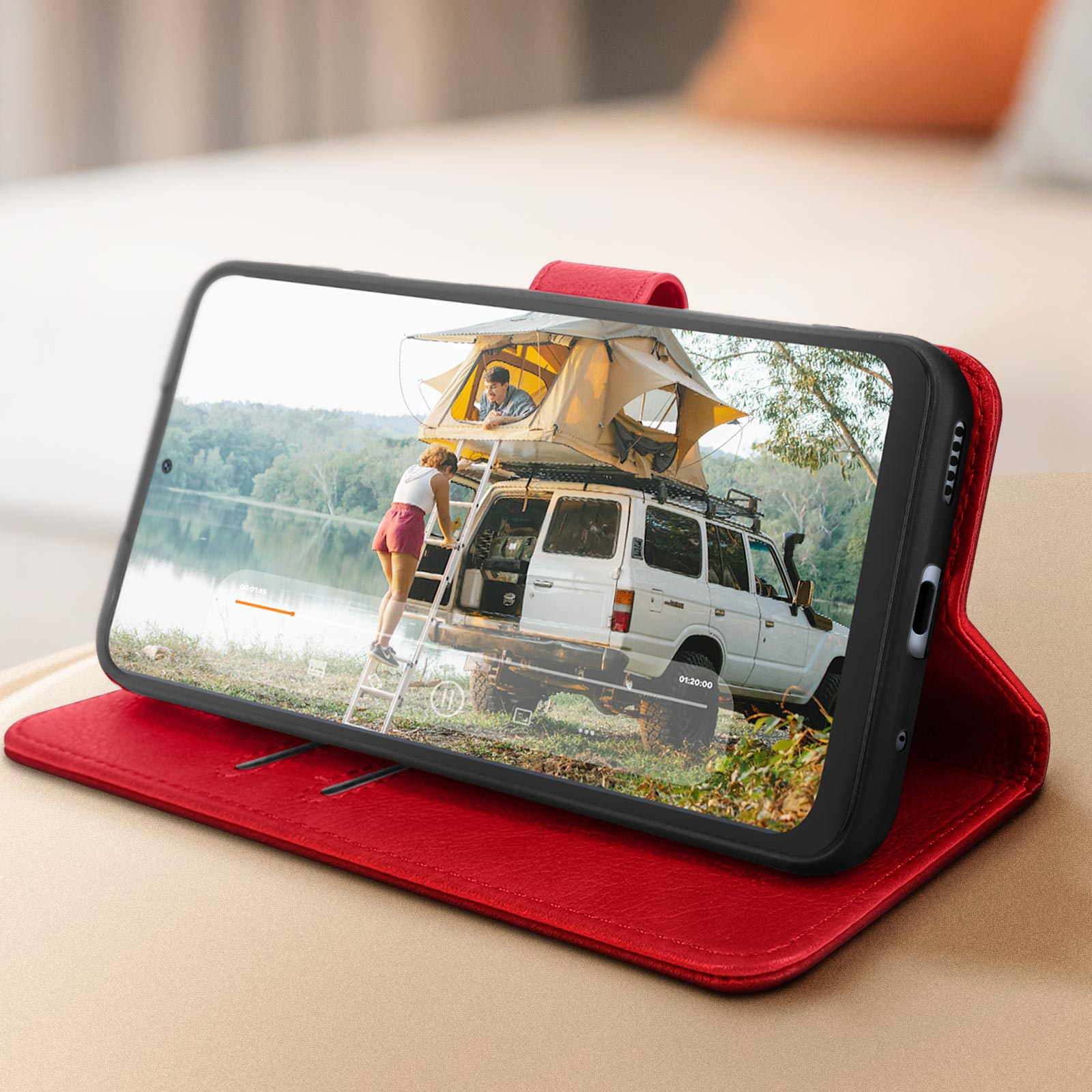 Un telefono in una custodia rossa che mostra un'auto con una tenda sul tetto vicino all'acqua.