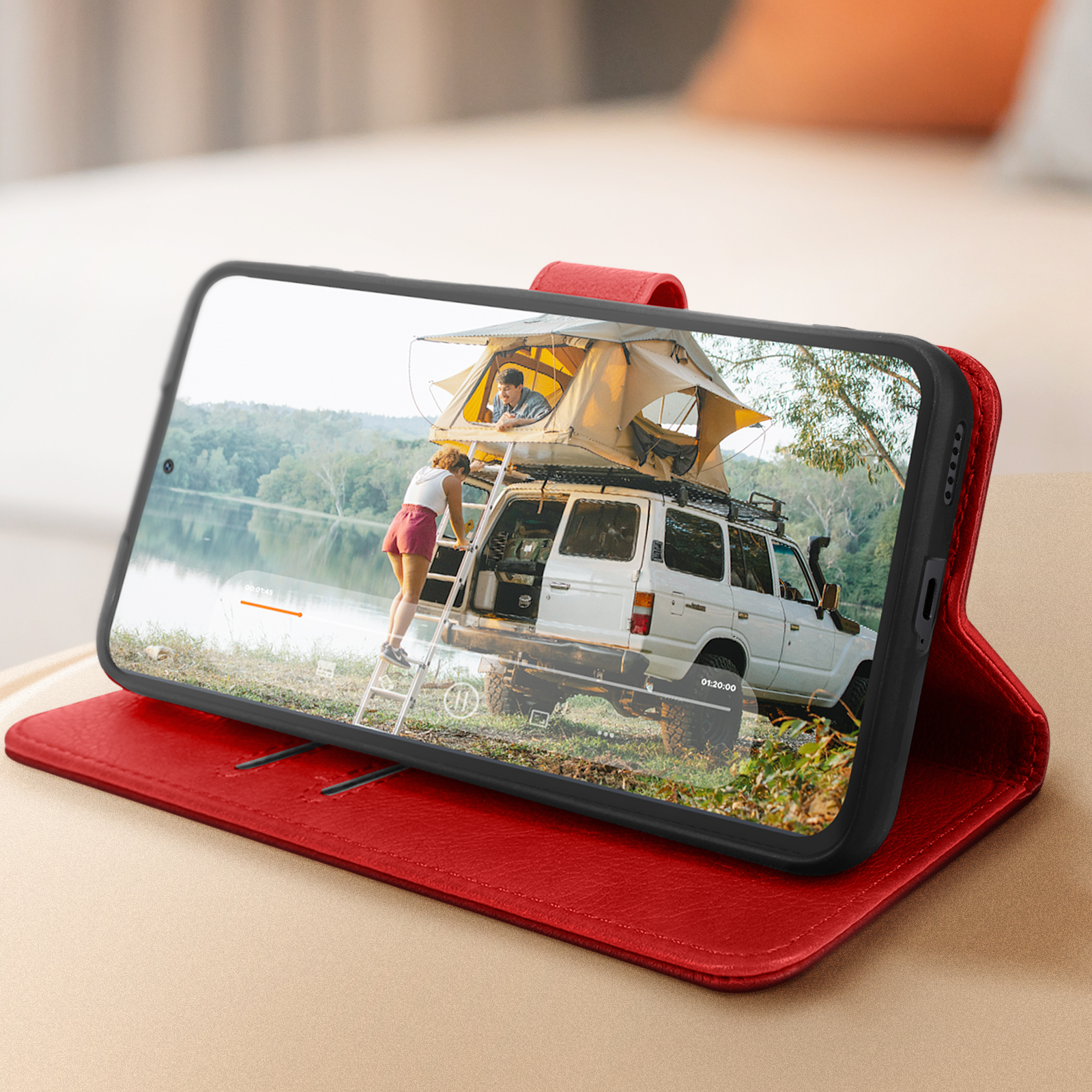 Uno smartphone in una custodia rossa che mostra una scena di campeggio con un'auto e persone.