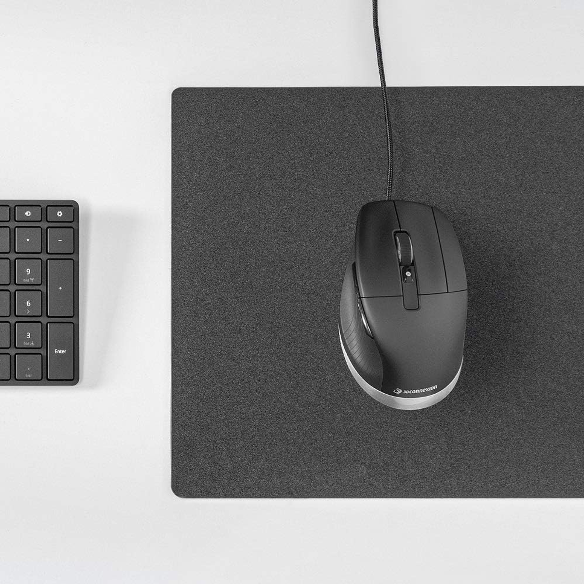 Czarna mysz i podkładka pod mysz obok czarnej klawiatury. Podkładka jest ciemnoszara.