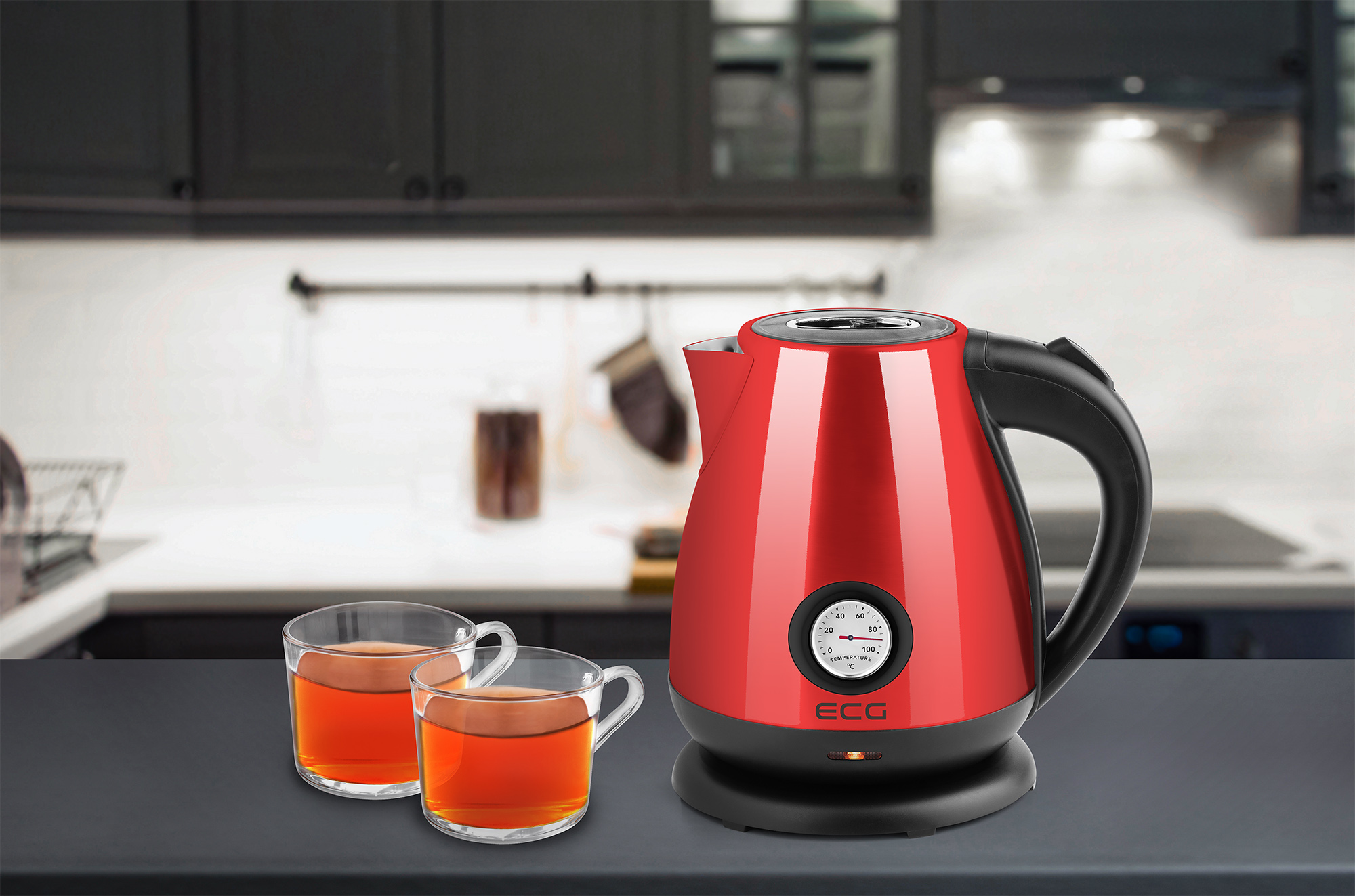Roter Wasserkocher und zwei Gläser mit Tee auf einer Küchenarbeitsplatte.