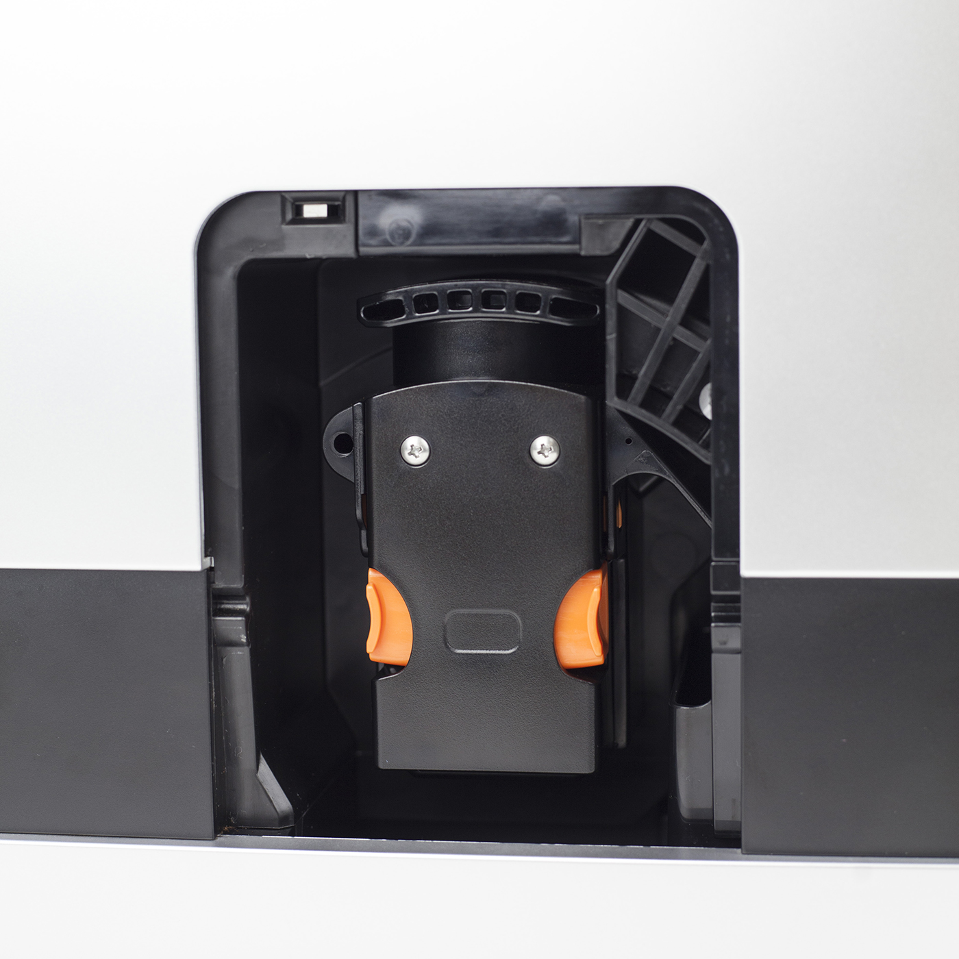 Nahaufnahme des Inneren eines schwarzen Geräts, das eine schwarze Komponente mit orangenen Clips zeigt.