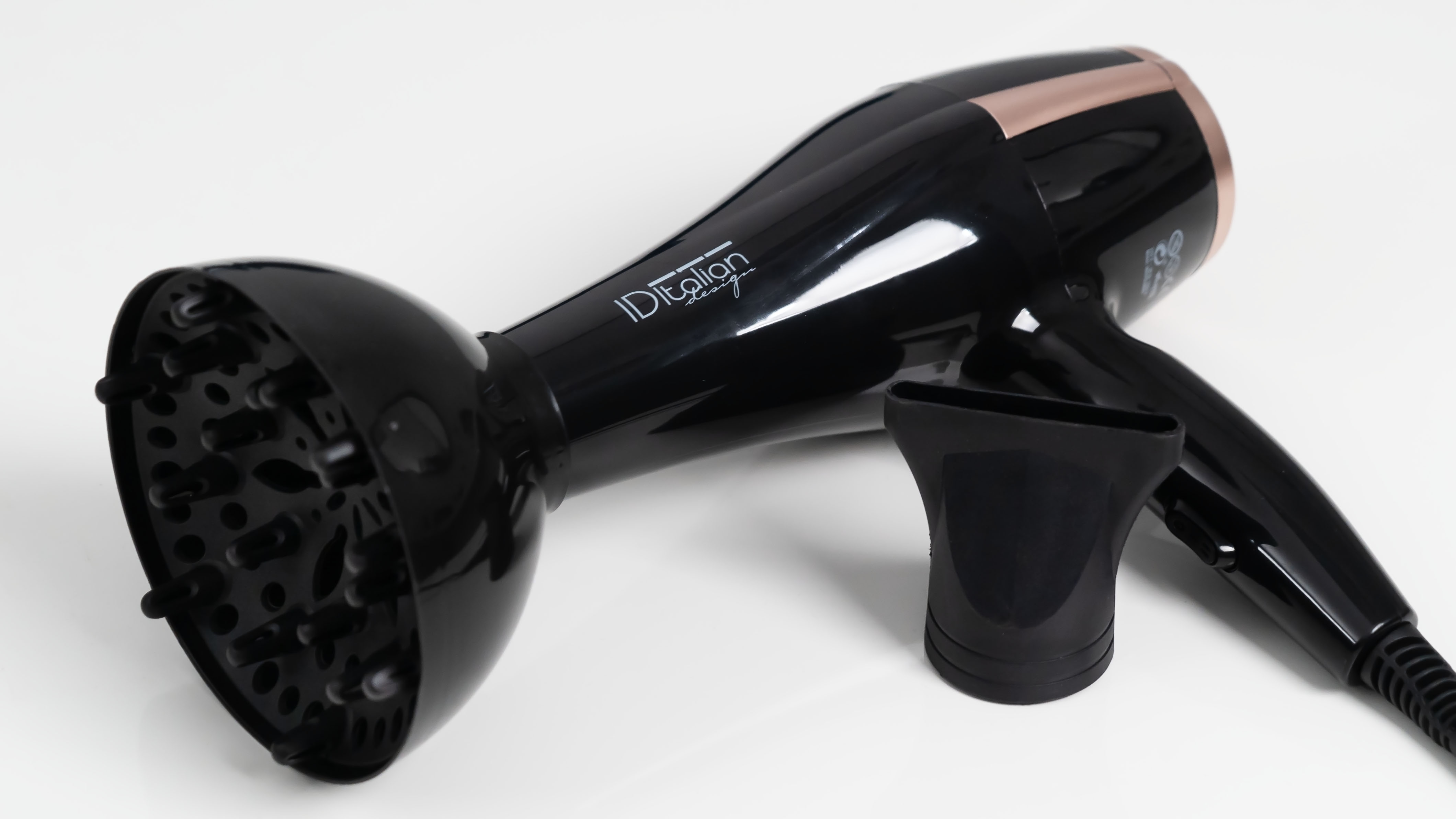 Czarna suszarka do włosów z dyfuzorem i dyszą na białej powierzchni.