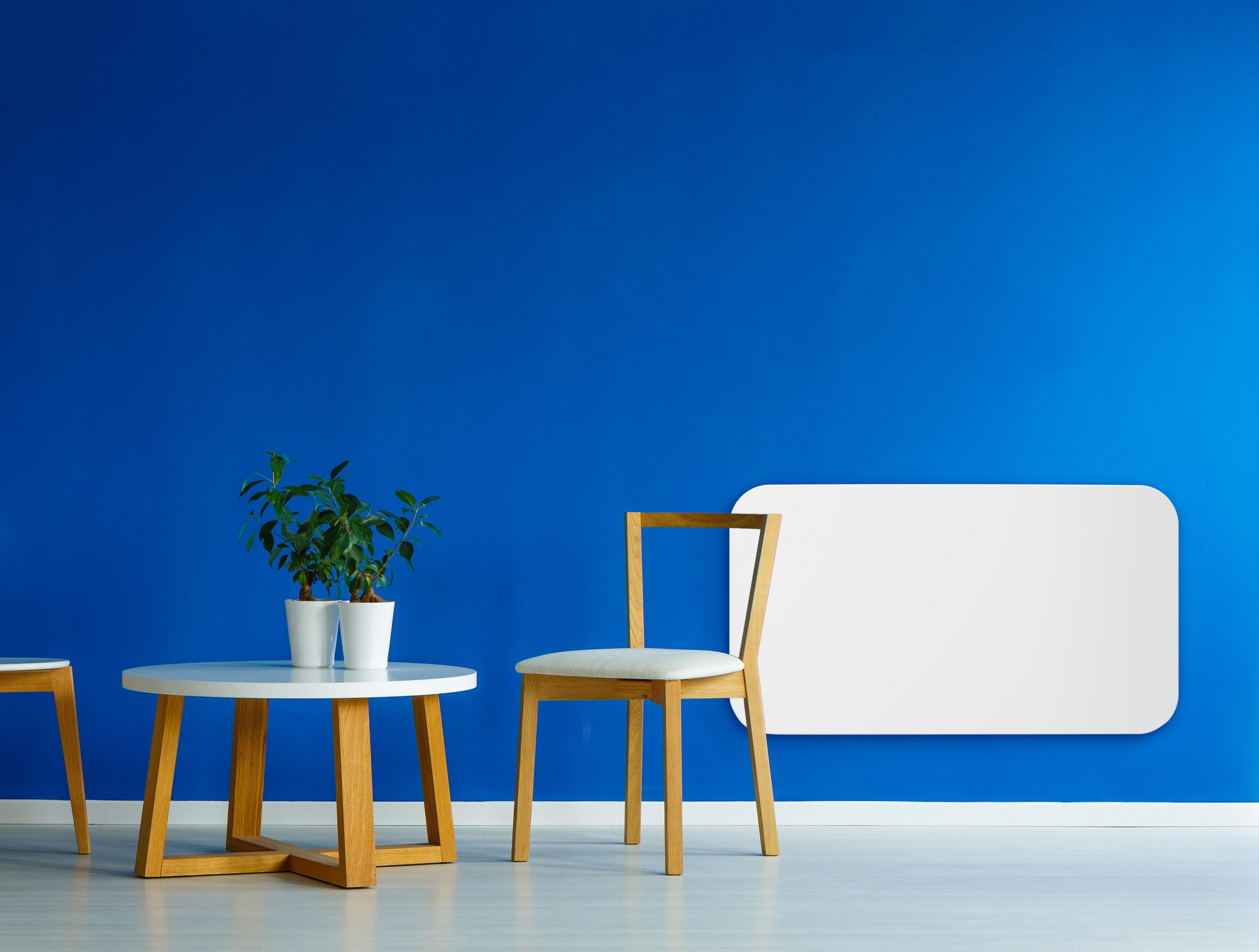 Una habitación con pared azul, mesa blanca, dos macetas blancas con planta y silla blanca.