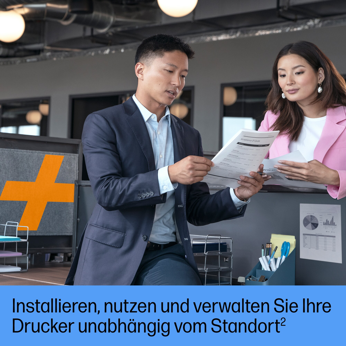 Dwie osoby przeglądają papiery w biurze. Mężczyzna w garniturze, kobieta w różu, pomarańczowe logo.