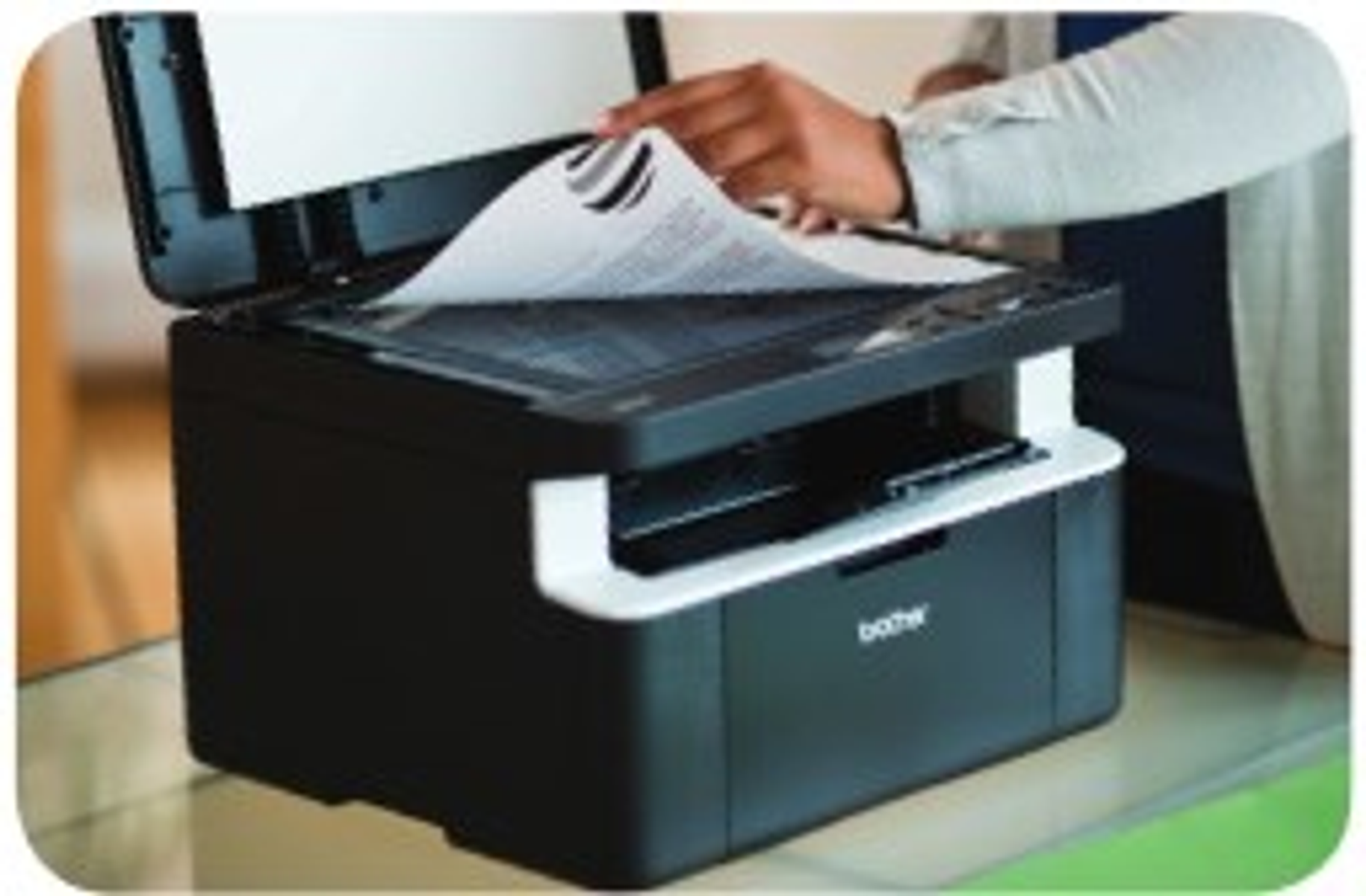Una persona colocando un papel en una impresora en blanco y negro. La impresora está abierta.