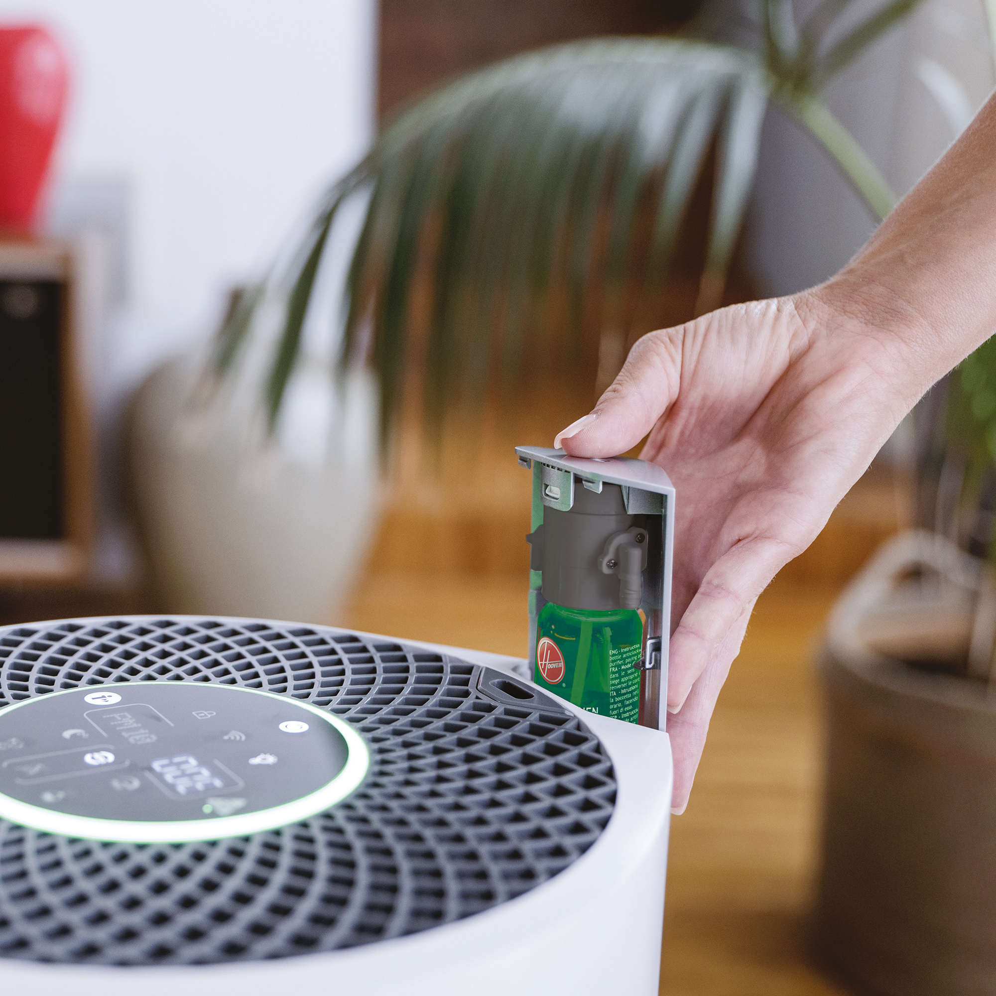 Una mano inserisce una cartuccia di liquido verde in un purificatore d'aria bianco.