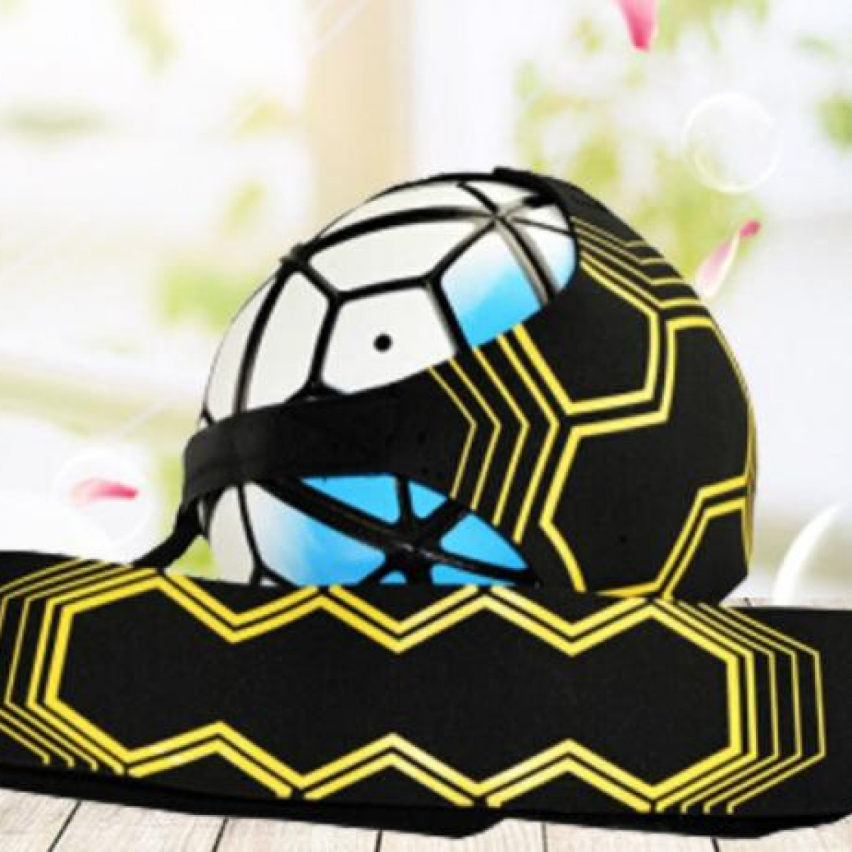 Pallone da calcio in un'imbracatura da allenamento nera e gialla. La palla è bianca con esagoni neri. Sfondo sfocato.