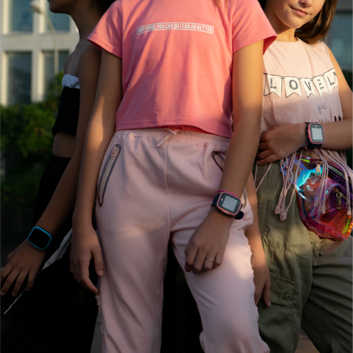 Tres chicas juntas, usando smartwatches y ropa casual. Hay luz solar.