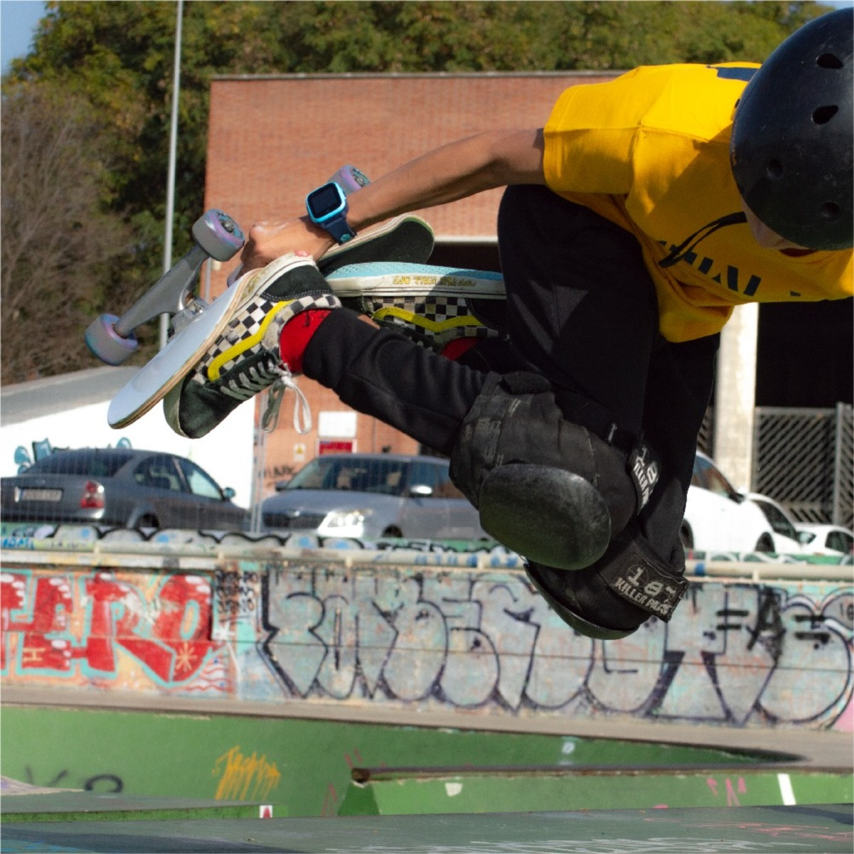 Un skater en el aire, realizando un truco, con graffiti en el fondo.