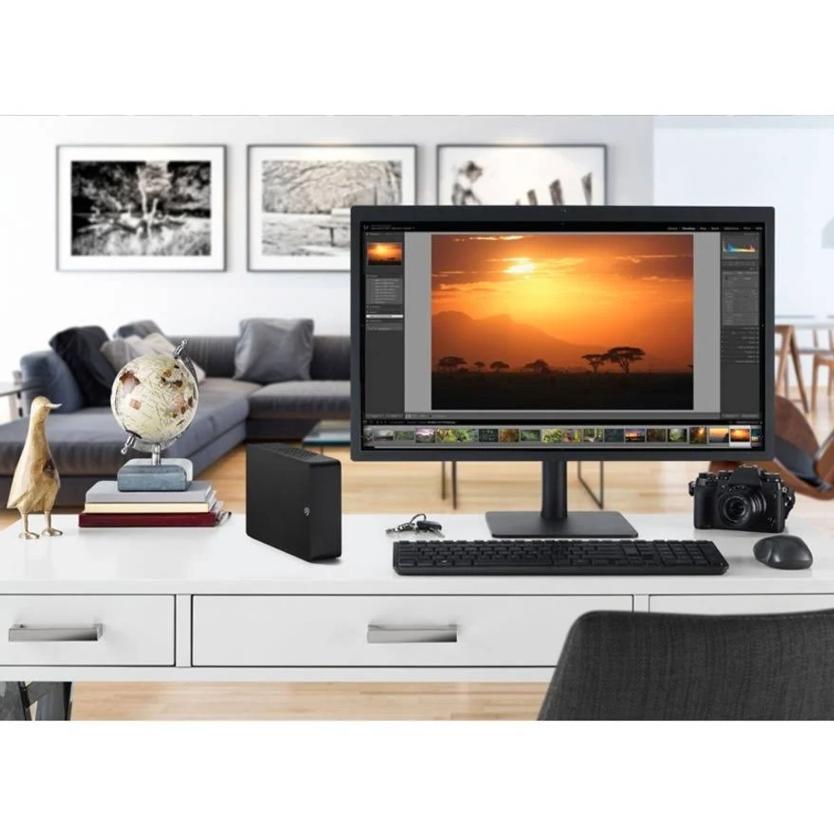 Configuration de bureau avec un moniteur affichant une image de coucher de soleil. Globe, clavier.