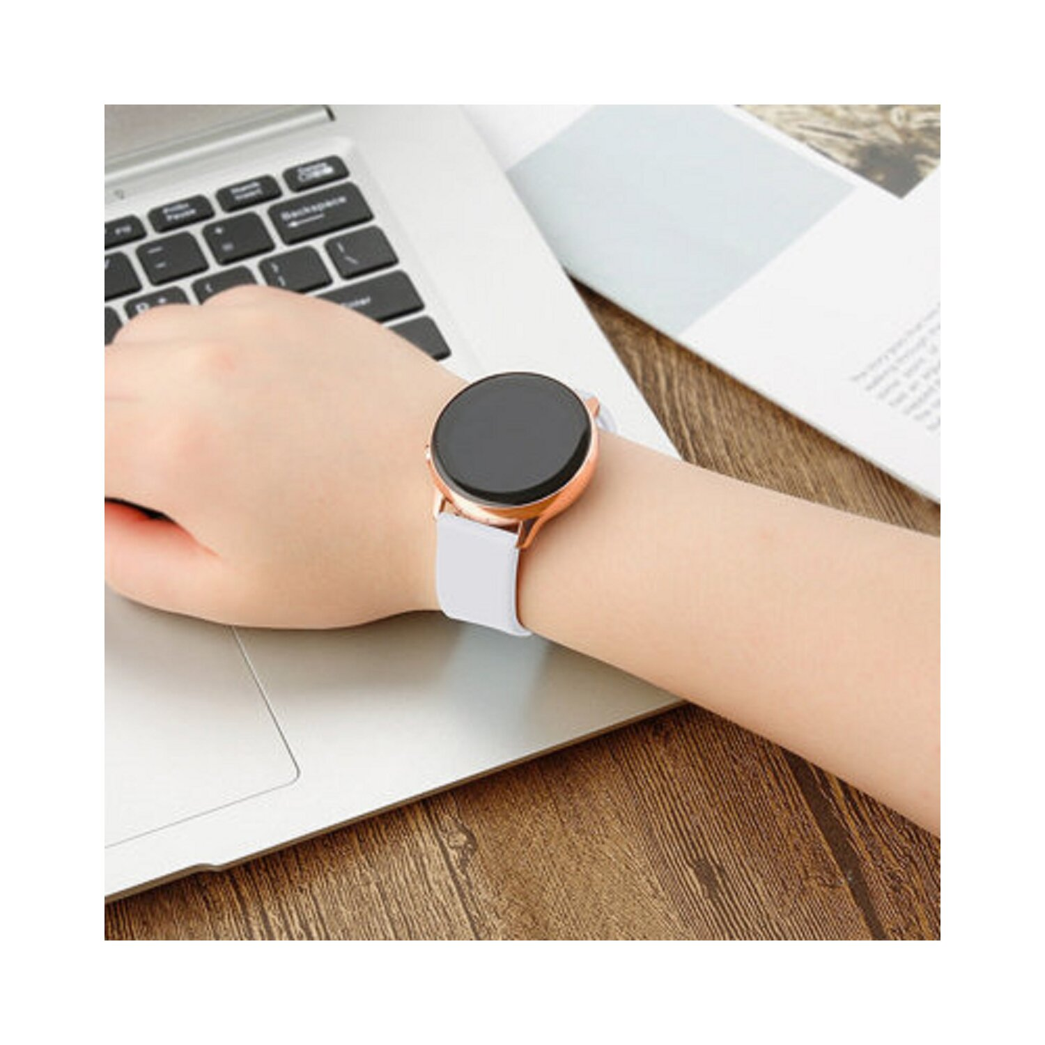 Das Handgelenk einer Person mit einer Smartwatch mit weißem Armband. Die Uhr hat ein roségoldenes Gehäuse und ein schwarzes Display.