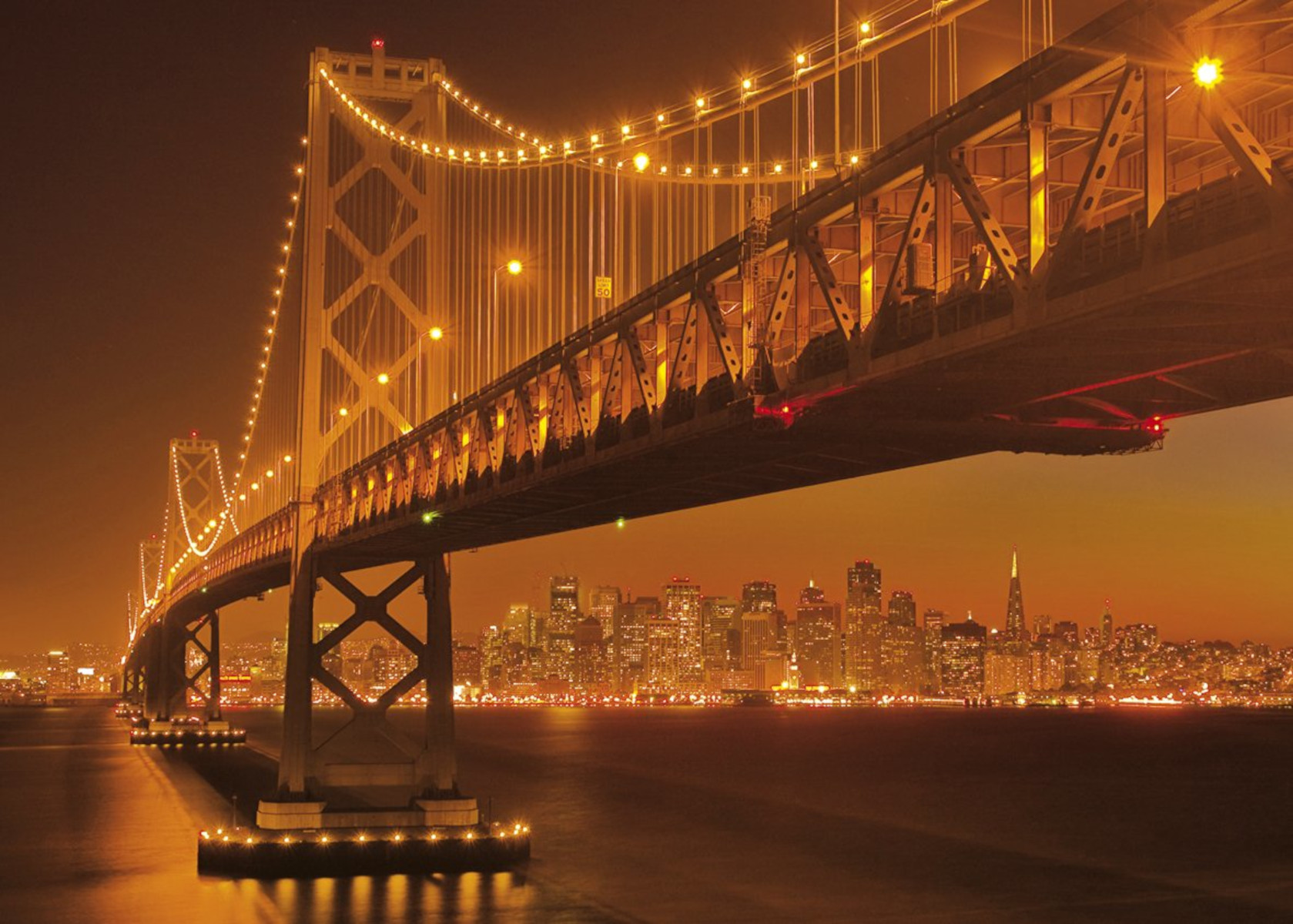 Nachtansicht der Golden Gate Bridge mit Stadtlichtern im Hintergrund.