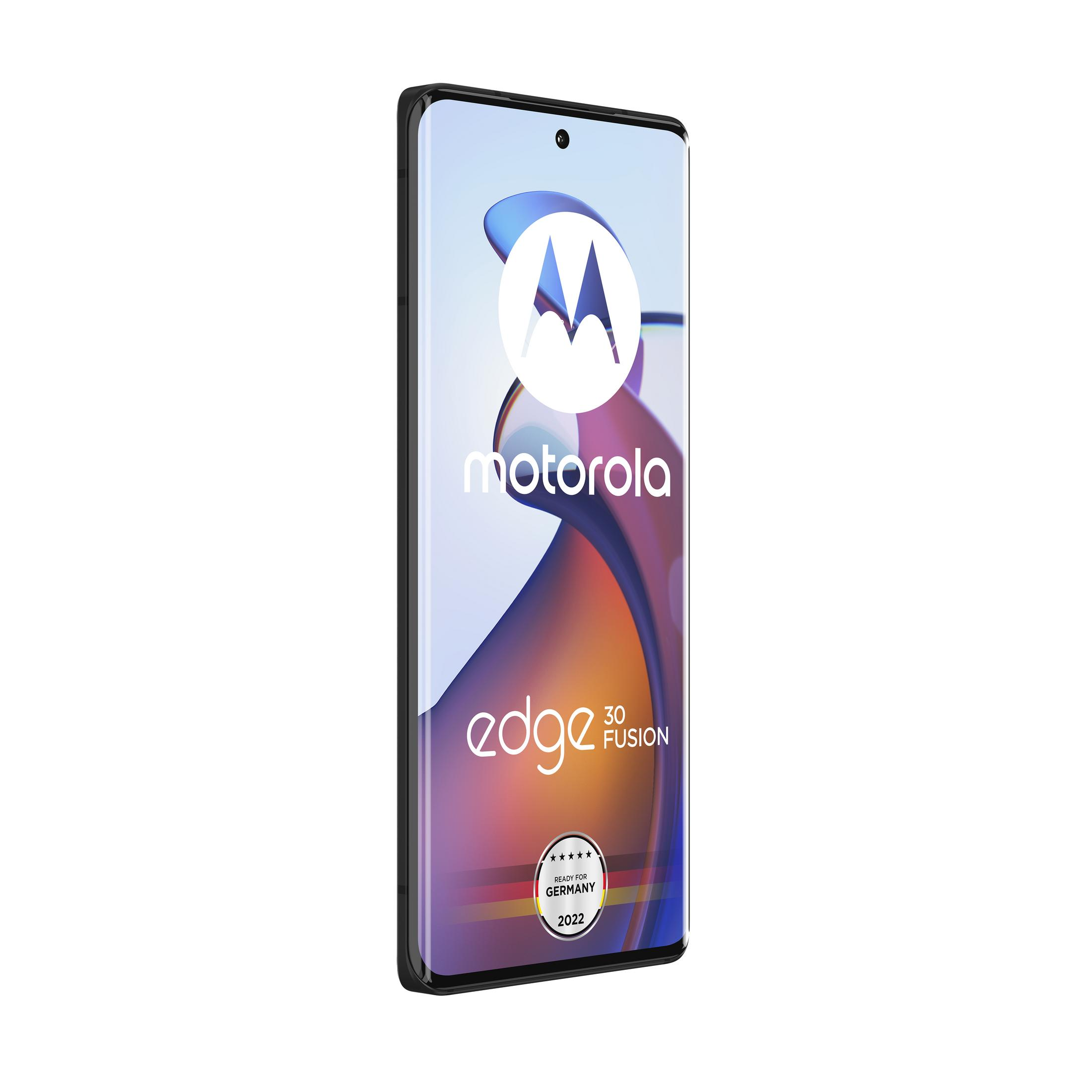 Telefon komórkowy Motorola Edge 30 Fusion. Czarna ramka, białe logo Motorola, niemiecka etykieta, białe tło.