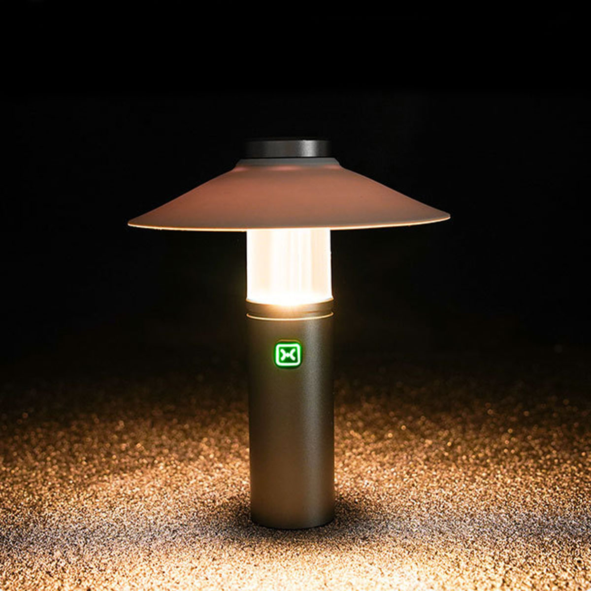 Eine kleine, moderne Lampe mit leuchtendem Oberteil, die auf einer Oberfläche glüht.