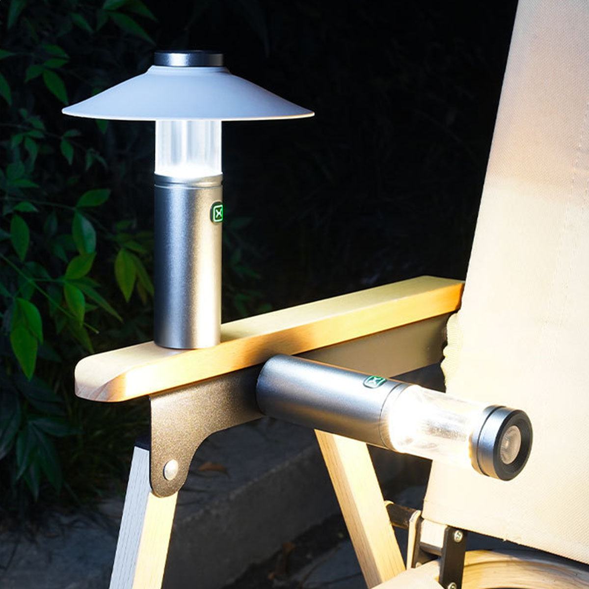 Zwei silberne Lampen auf Holzarmlehne. Eine aufrecht, die andere horizontal.