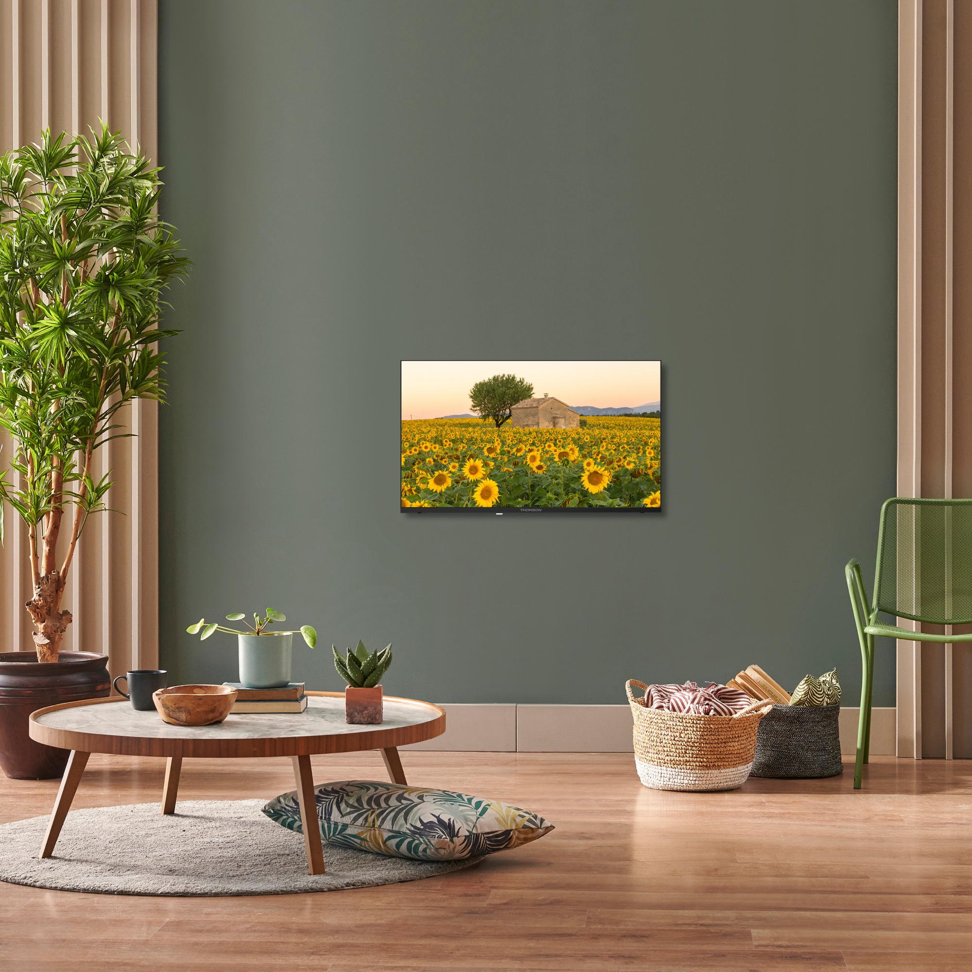 Salón con pintura de girasoles. Pared verde, suelo de madera. Una silla y una mesa.