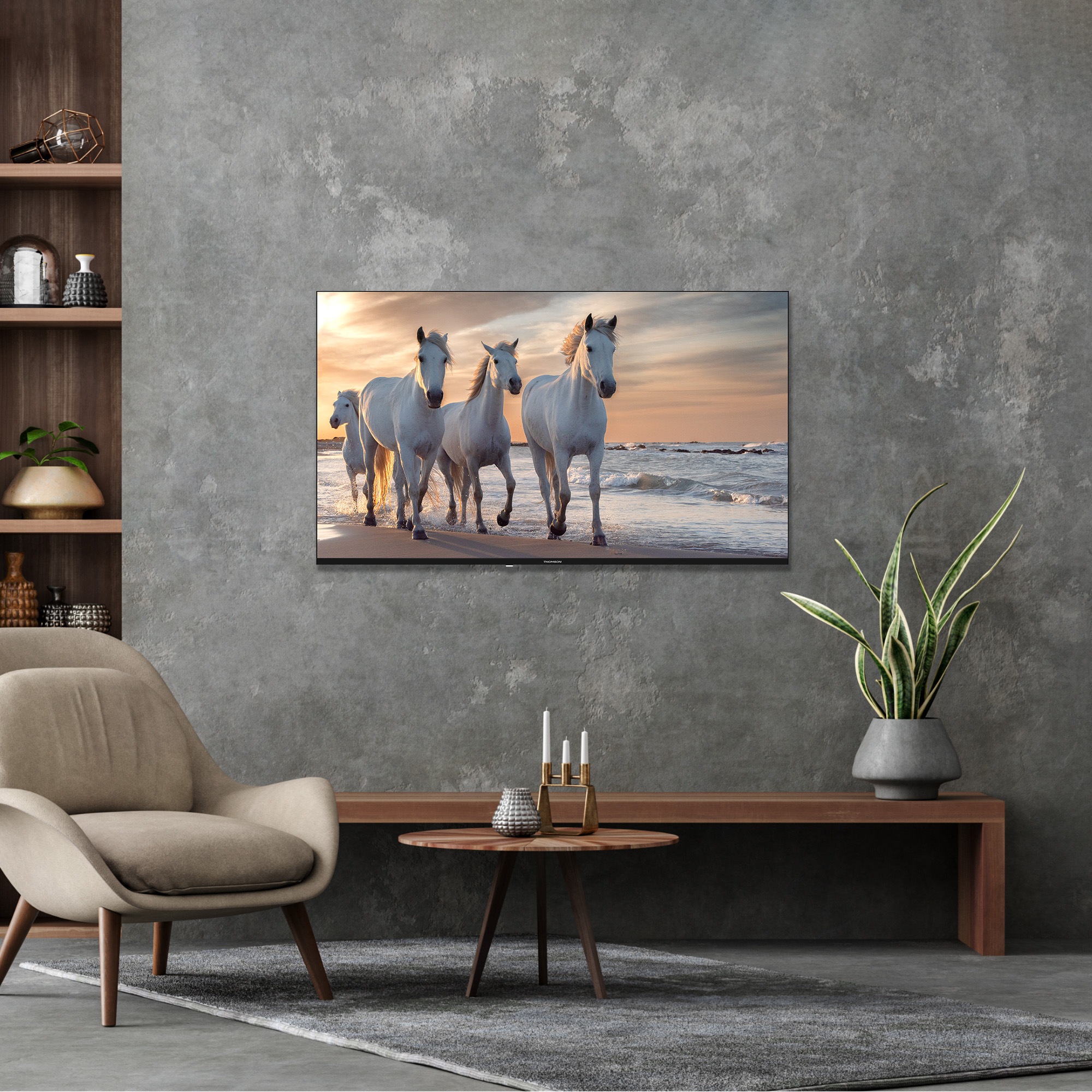 Schermo TV che mostra cavalli bianchi sulla spiaggia al tramonto. Interni con decorazioni e piante.