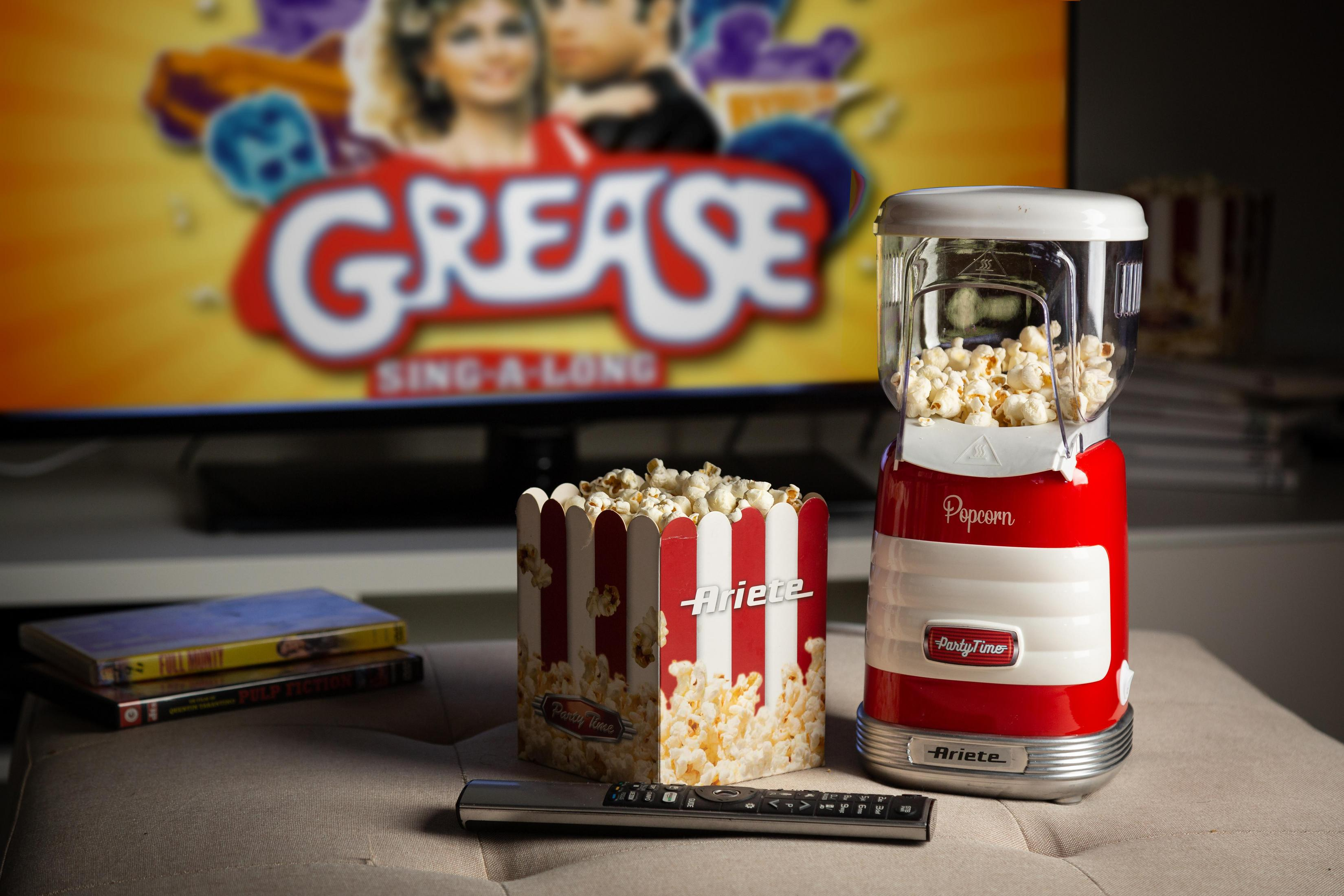 Grease filmini gösteren bir TV'nin önünde patlamış mısır ve bir patlamış mısır makinesi.