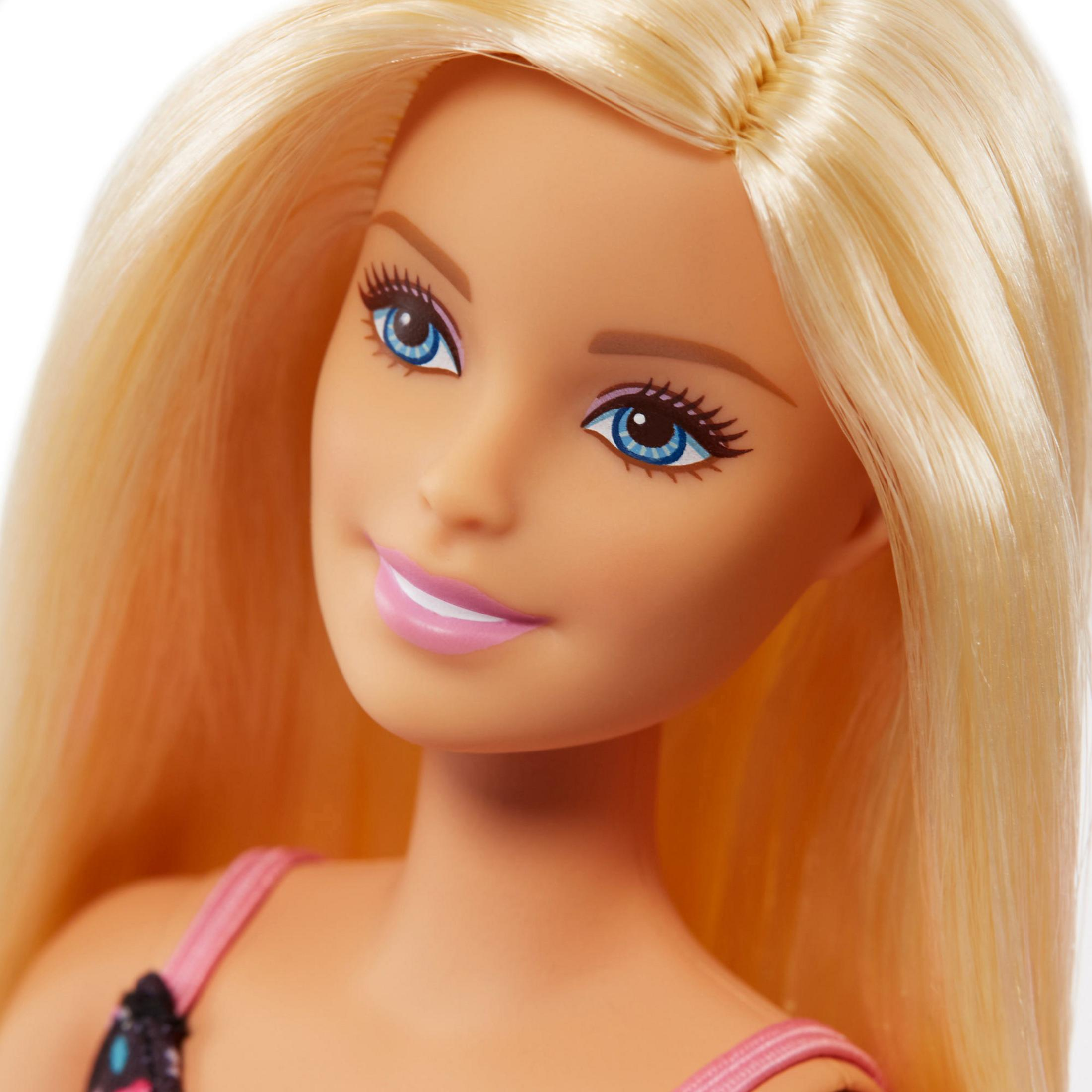 Zbliżenie lalki Barbie z blond włosami i niebieskimi oczami. Różowa sukienka na ramiączkach, uśmiechnięta.