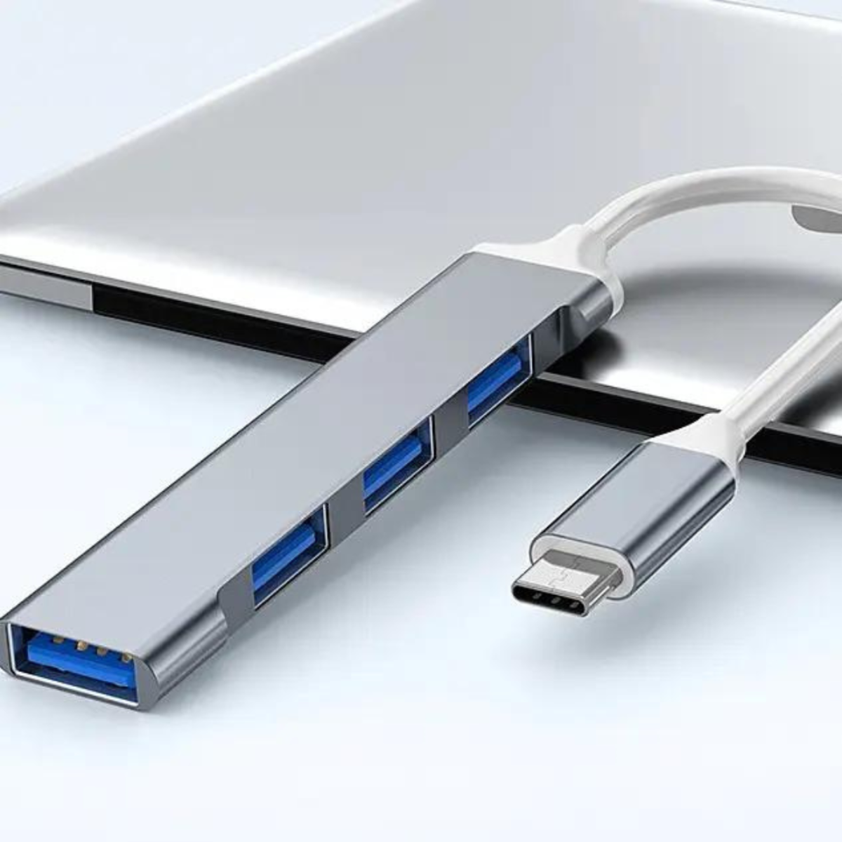 Silberner USB-Hub mit vier blauen USB-Anschlüssen und einem Typ-C-Anschluss. Weißer Hintergrund.