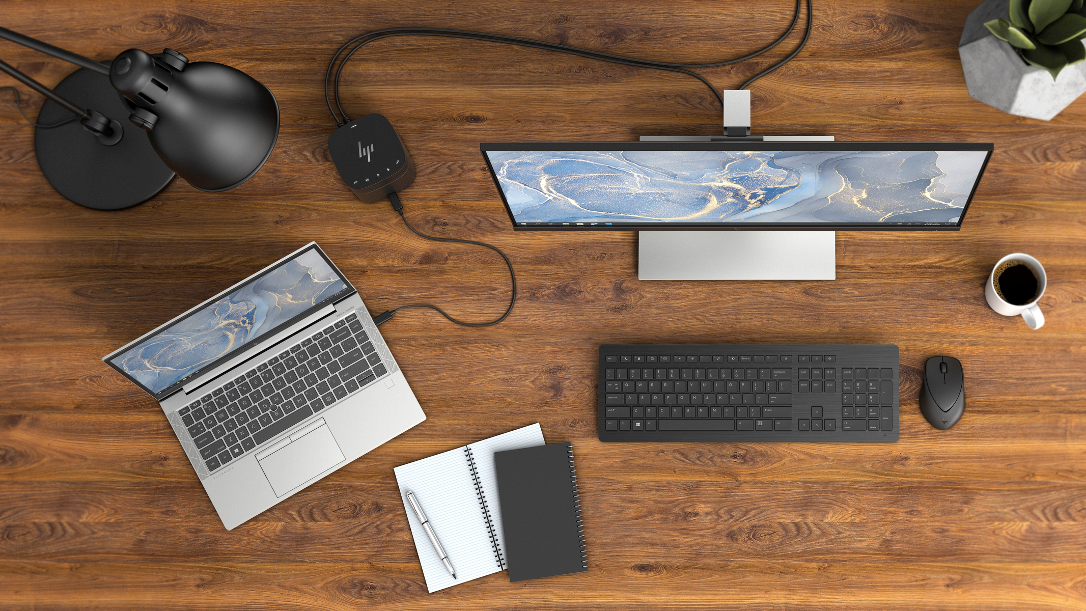 Draufsicht auf einen Schreibtisch. Laptop, Monitor, Tastatur, Maus, Notizbuch und Kaffee.