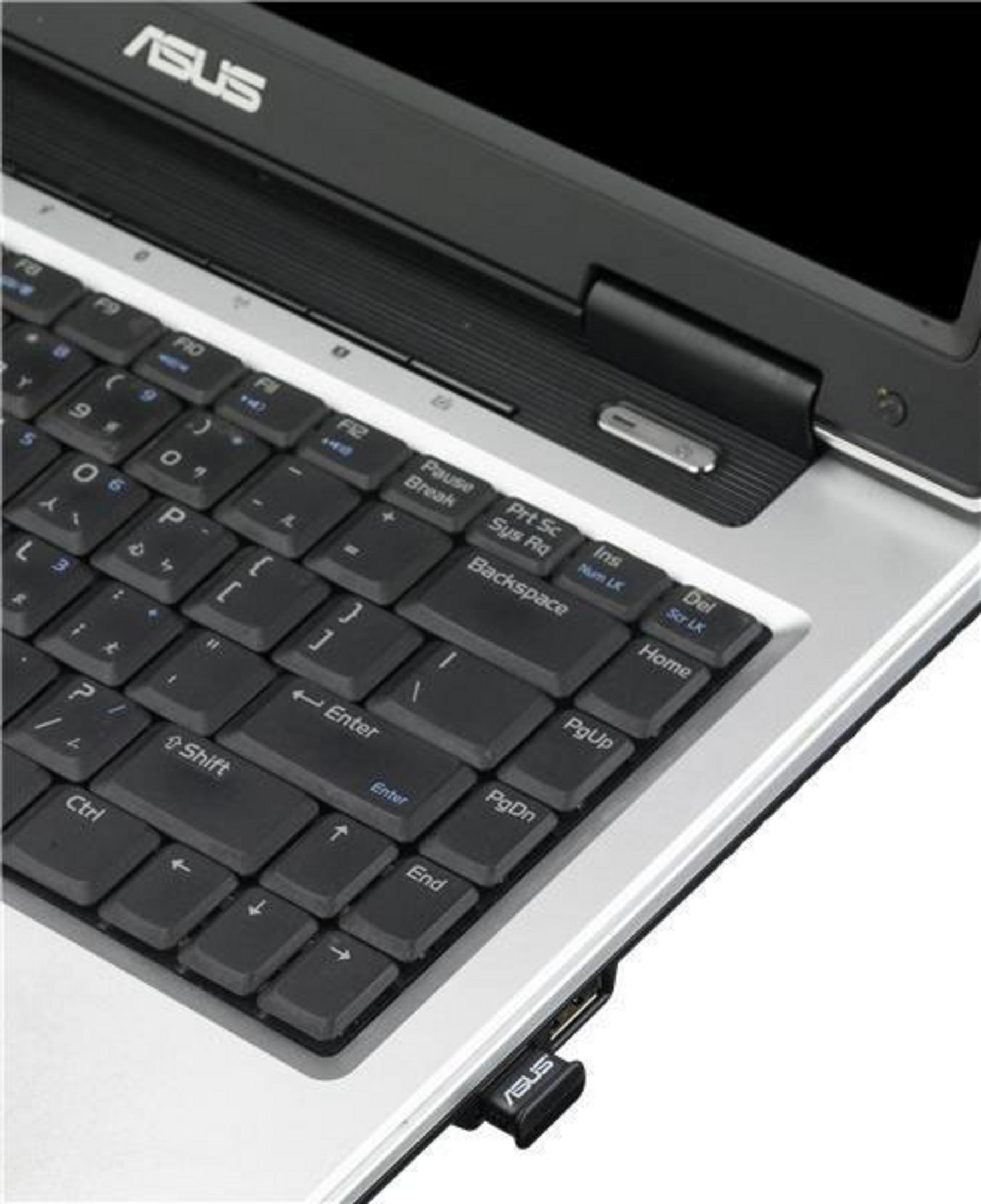 Primer plano del teclado del portátil, que revela un dongle USB de ASUS.