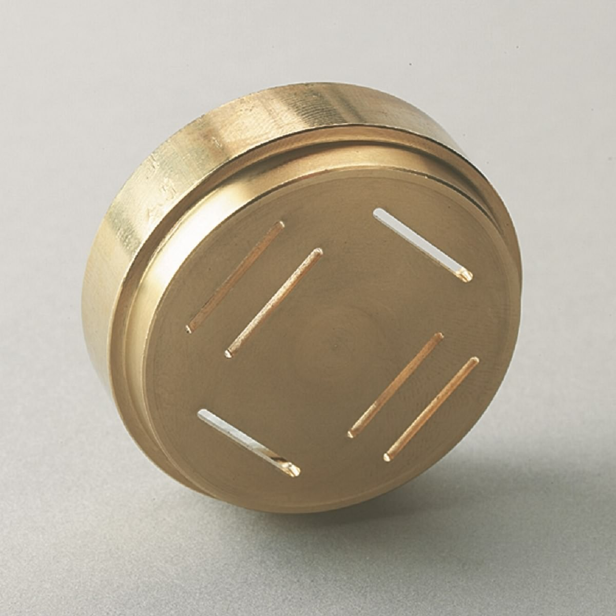 Nahaufnahme eines goldfarbenen Nudelmaschinenaufsatzes. Mit 4 Löchern zum Formen von Nudeln.
