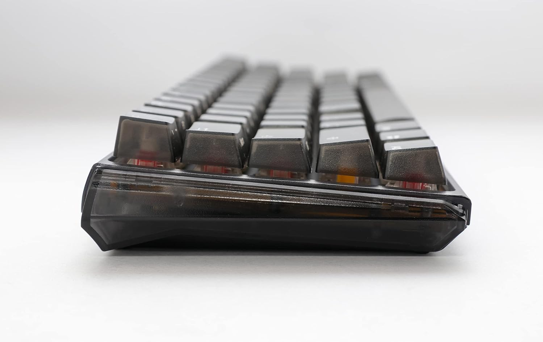 Widok z boku czarnej klawiatury mechanicznej z czarnymi nakładkami na białym tle.