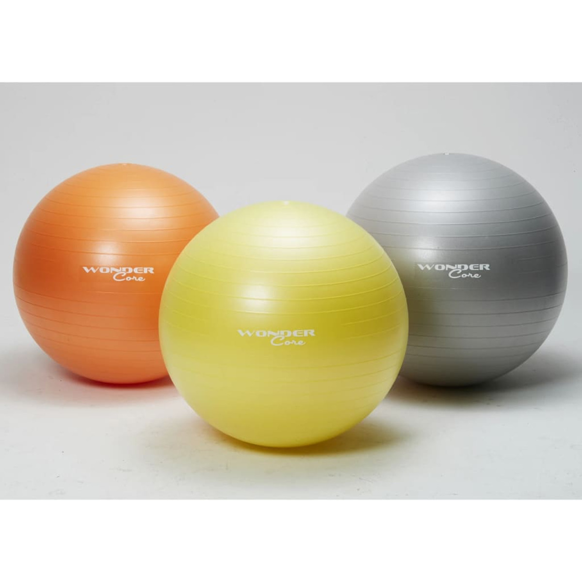 Drei Gymnastikbälle. Orange, gelb und silber. Weißer Hintergrund.