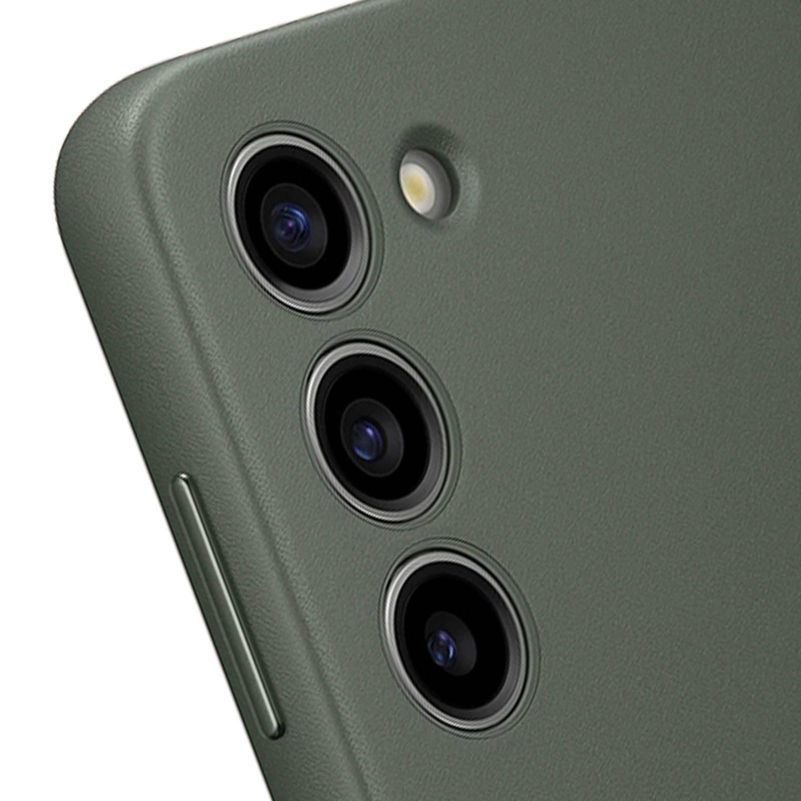 Primo piano del modulo fotocamera di un telefono con tre obiettivi e un flash, su una superficie verde.