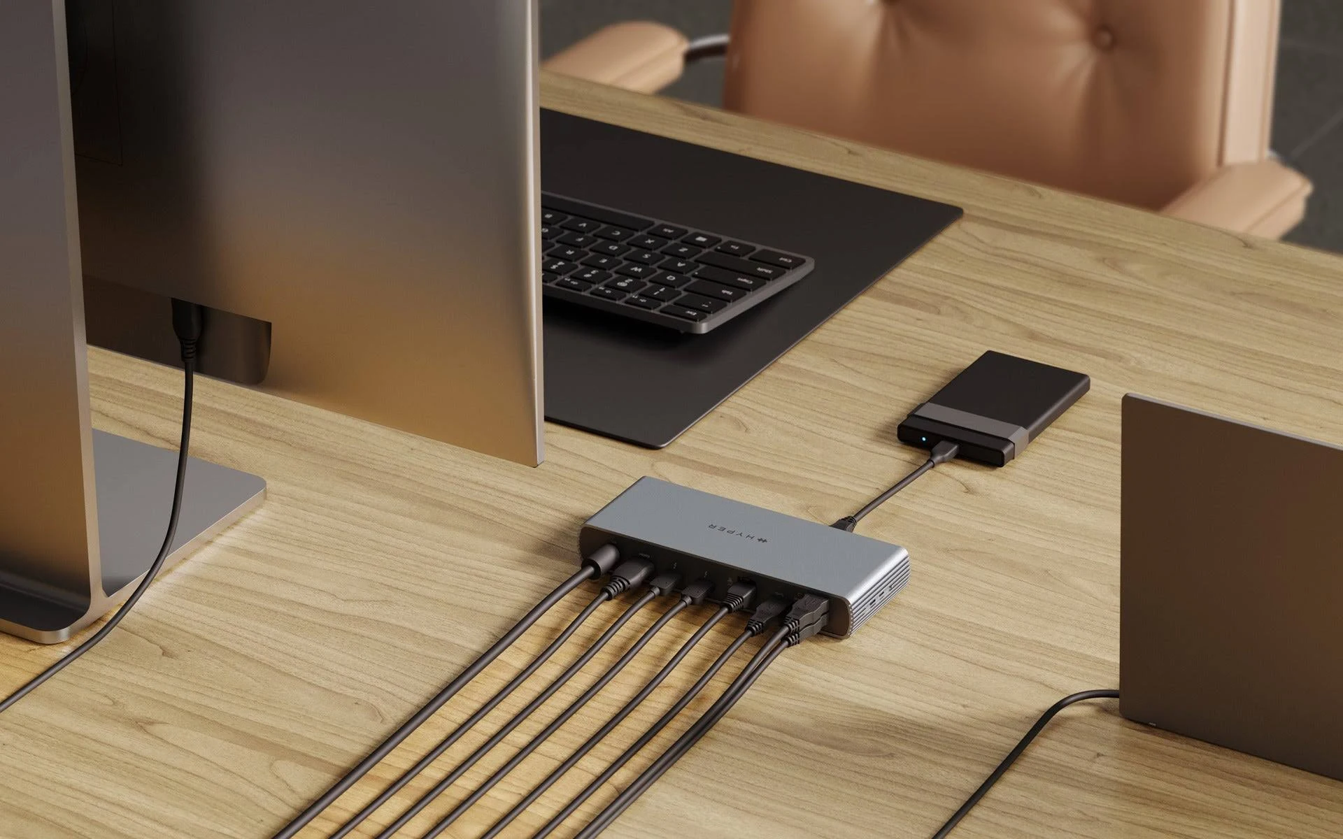 Ein Schreibtisch mit Monitor, Laptop und Hub mit mehreren angeschlossenen Kabeln.