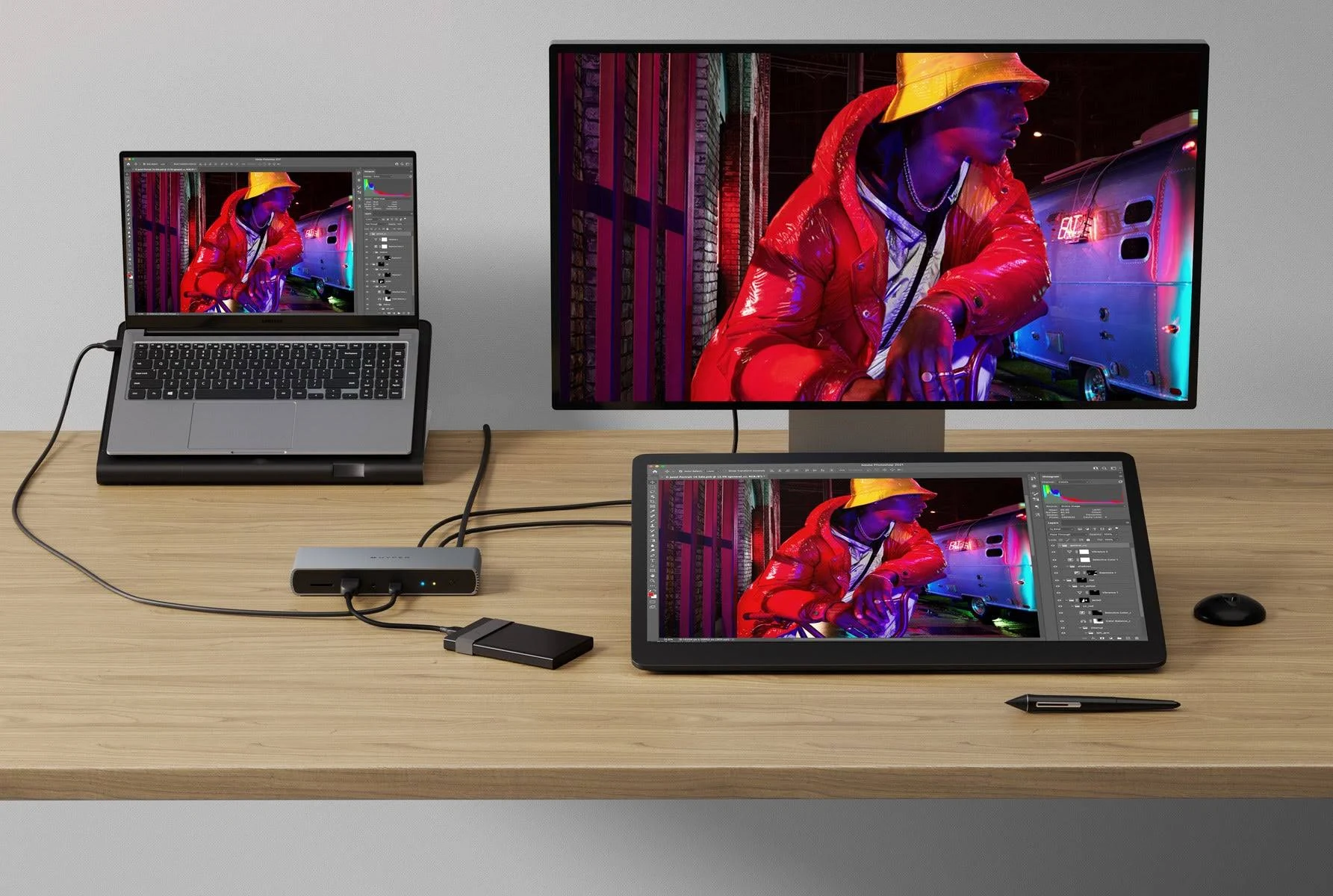 Desktop-Setup mit Laptop und Monitor. Tablet mit Stift. Zubehör und Kabel auf einem Holzschreibtisch.