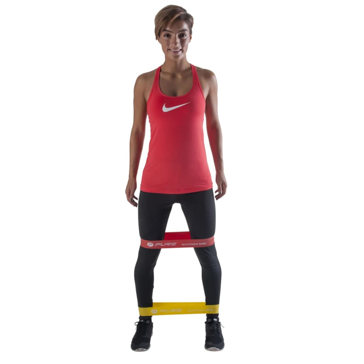 Frau in rotem Tanktop und schwarzer Leggings trainiert mit gelbem Widerstandsband.