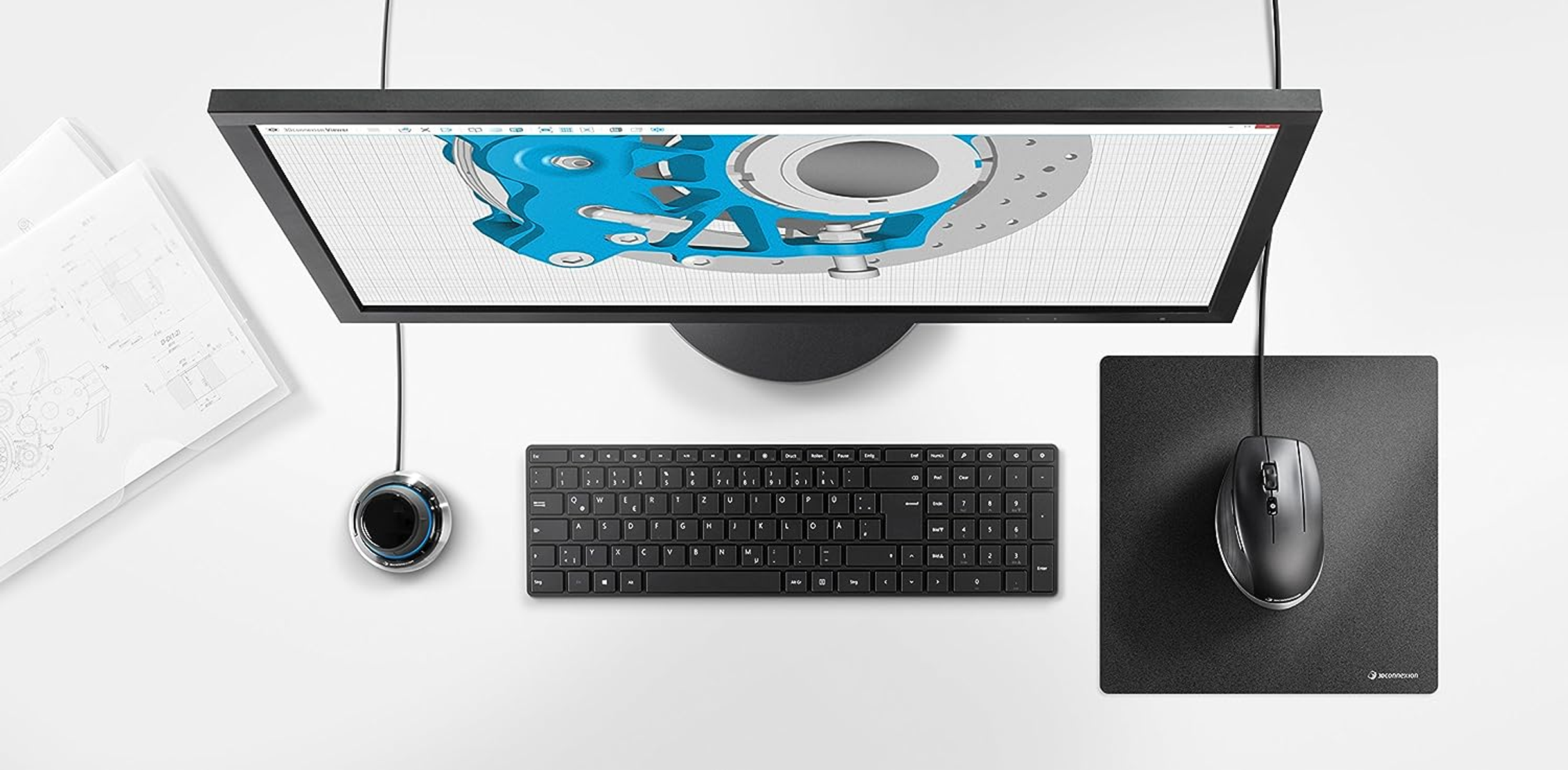 Draufsicht auf ein Setup: Monitor, Tastatur, Maus und ein Bedienknopf.