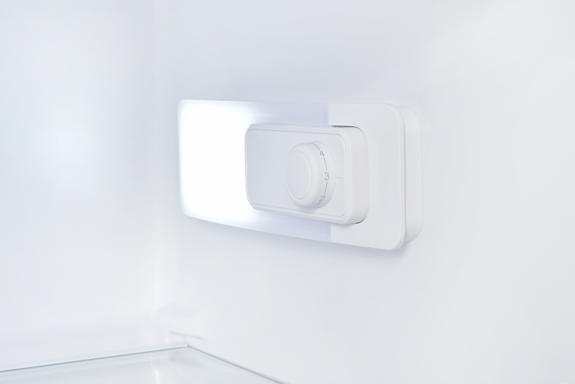 White refrigerator interior with a white dial and light.