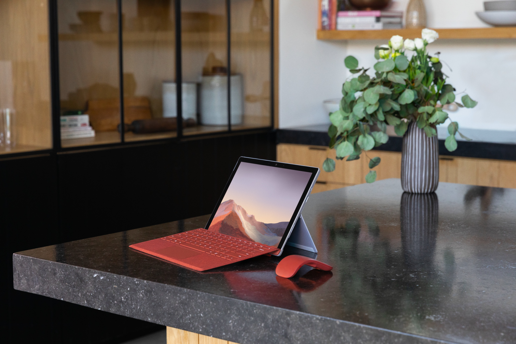 Tablet con tastiera e mouse su un piano di lavoro, con sfondo cucina.