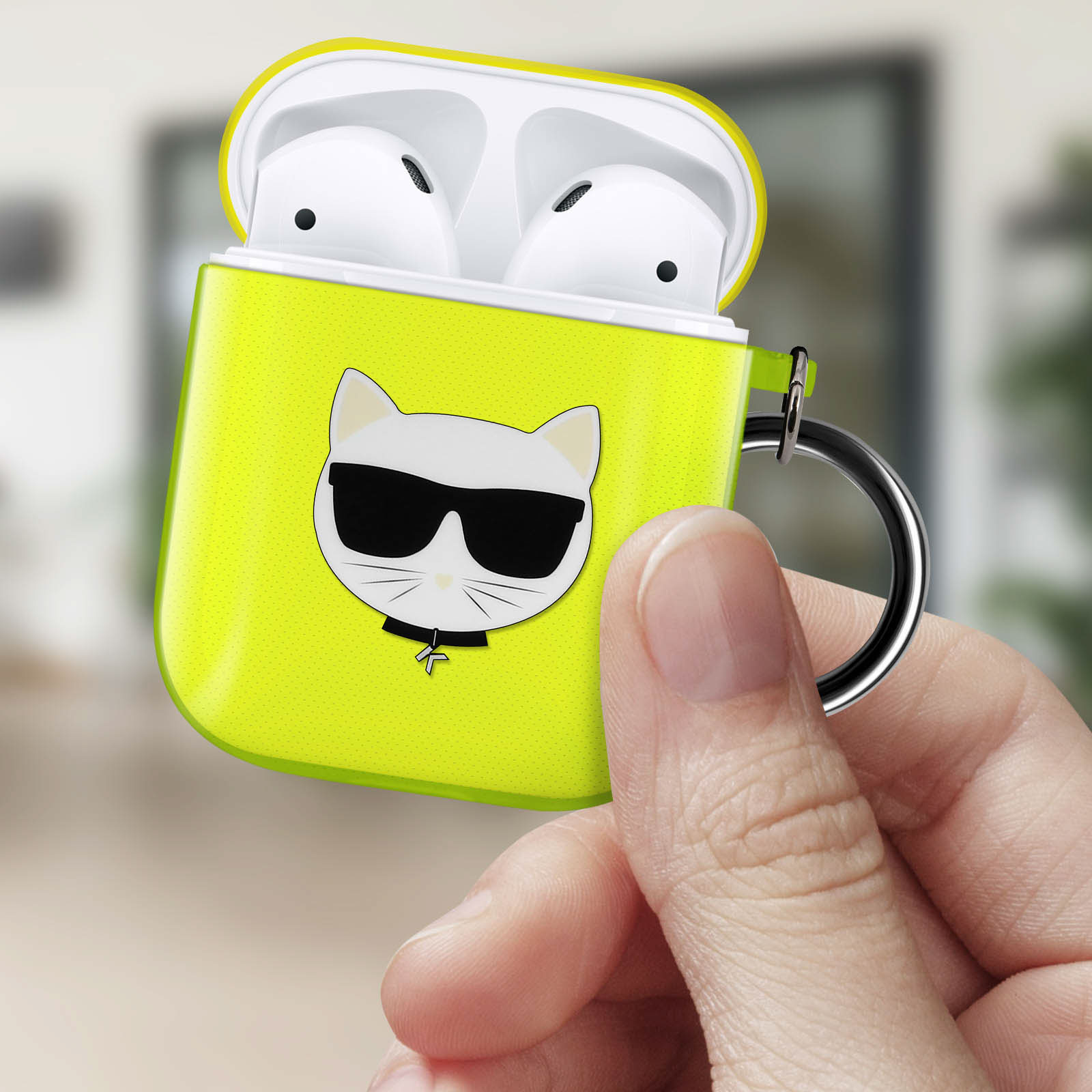 Una funda amarilla de AirPods con diseño de gato con gafas de sol, sostenida por una mano.