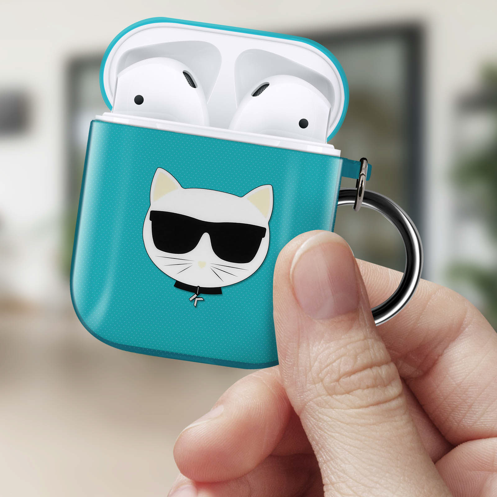 Türkisfarbenes Case mit weißen AirPods, Katzen-Grafik, Hand hält es.