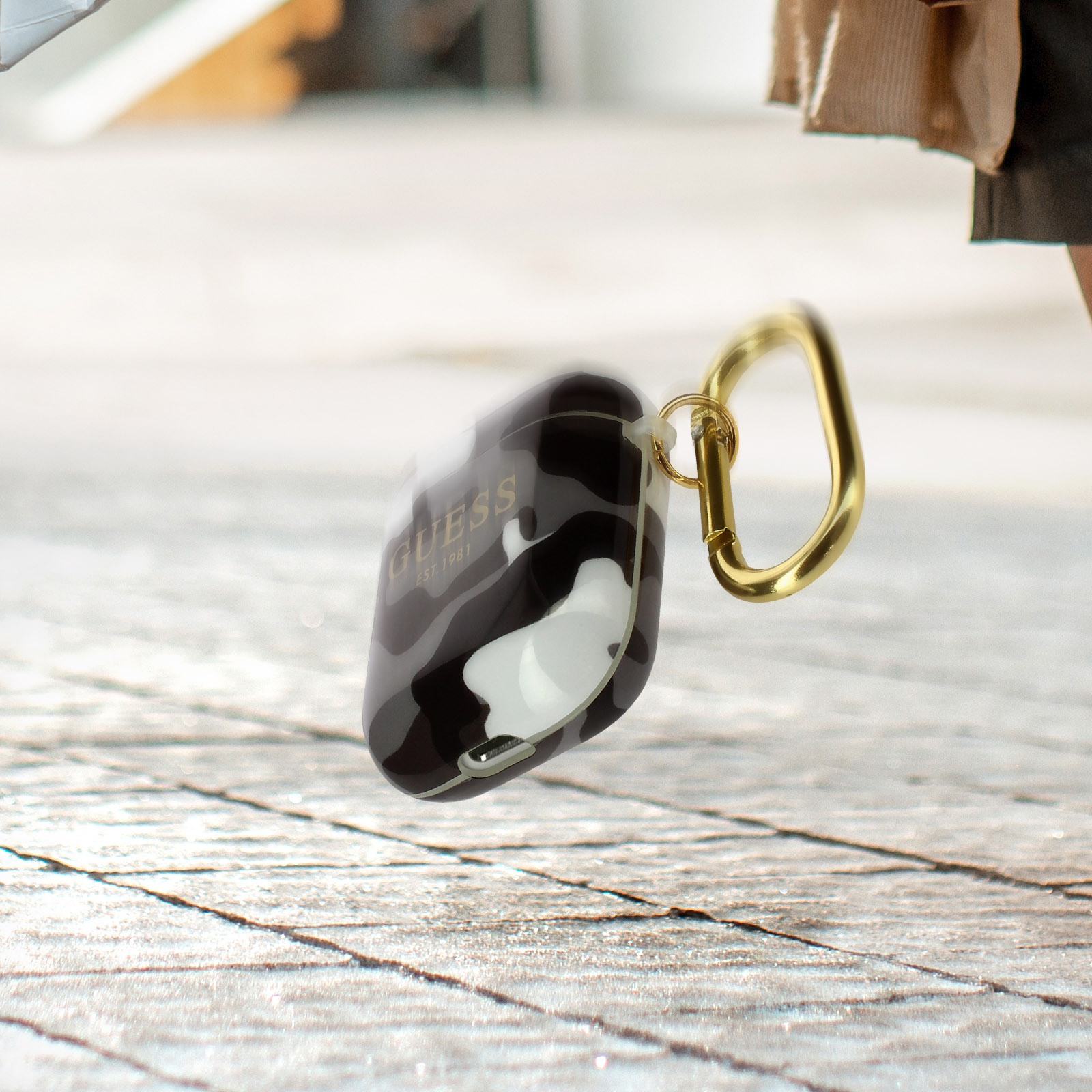 Funda para Airpods Guess en blanco y negro con un gancho dorado. Estampado de camuflaje.