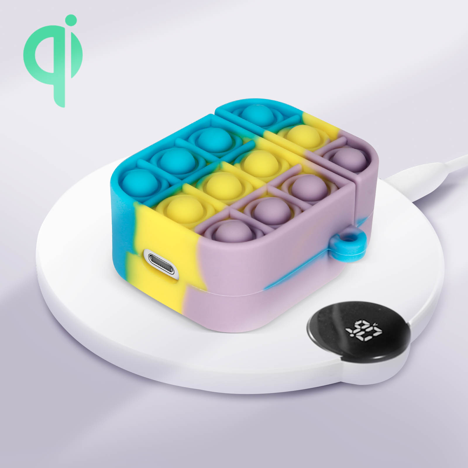 Un juguete pop-it colorido en un estuche, sobre una plataforma de carga inalámbrica, con un indicador de carga.