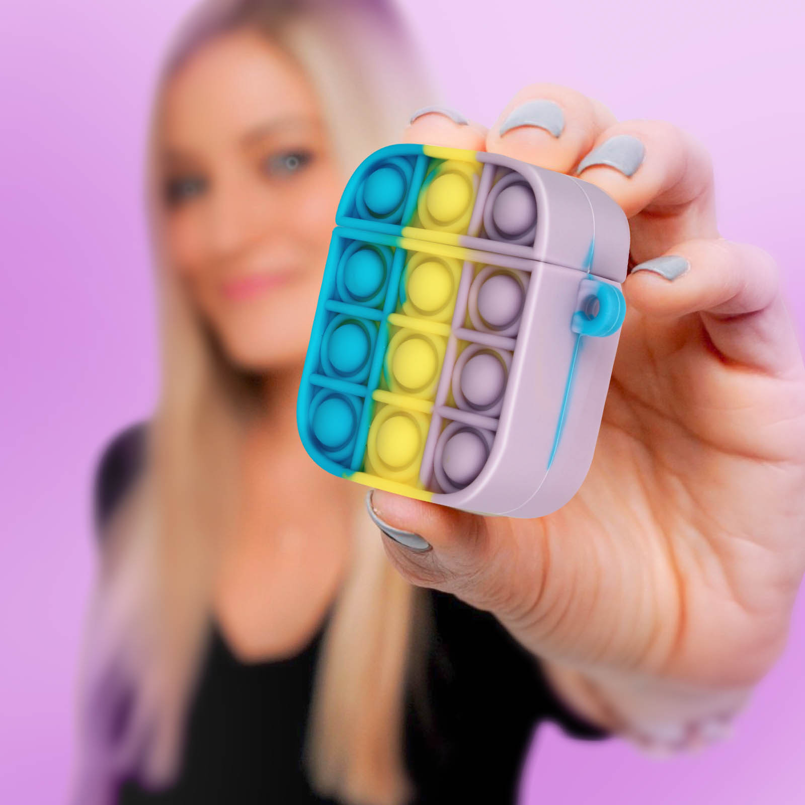 Mujer sosteniendo un estuche pop-it colorido para AirPods. Fondo morado.