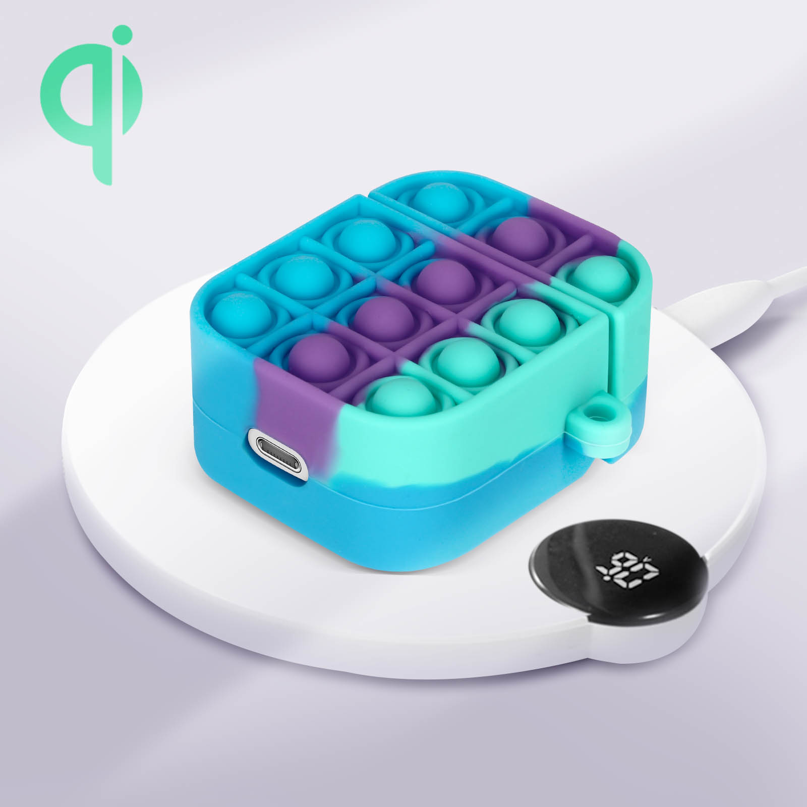 Una funda azul, morada y verde azulado tipo pop-it para auriculares inalámbricos, en un cargador inalámbrico blanco.
