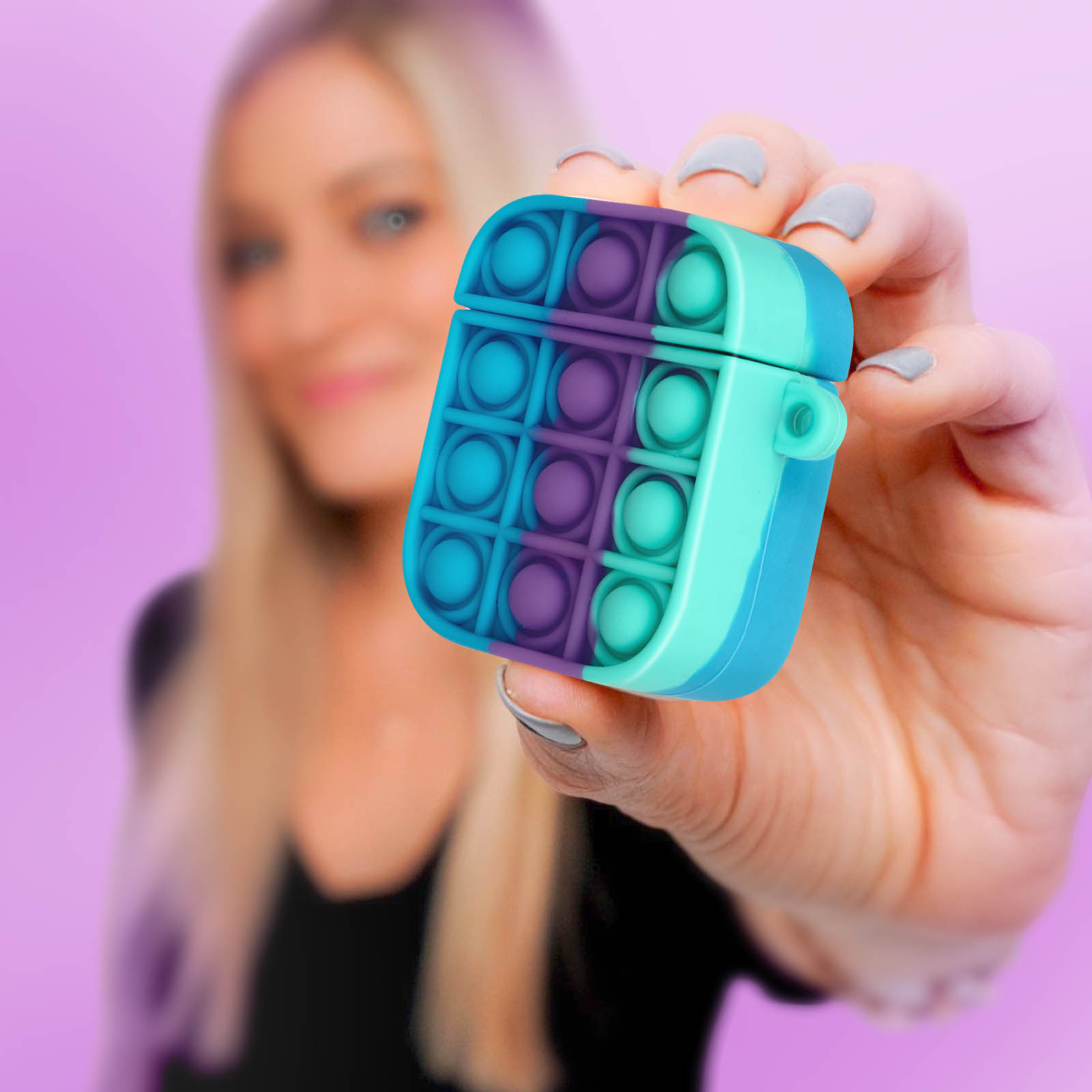 Una mujer sosteniendo una colorida funda Pop It AirPod. La funda es azul, morada y verde azulado.