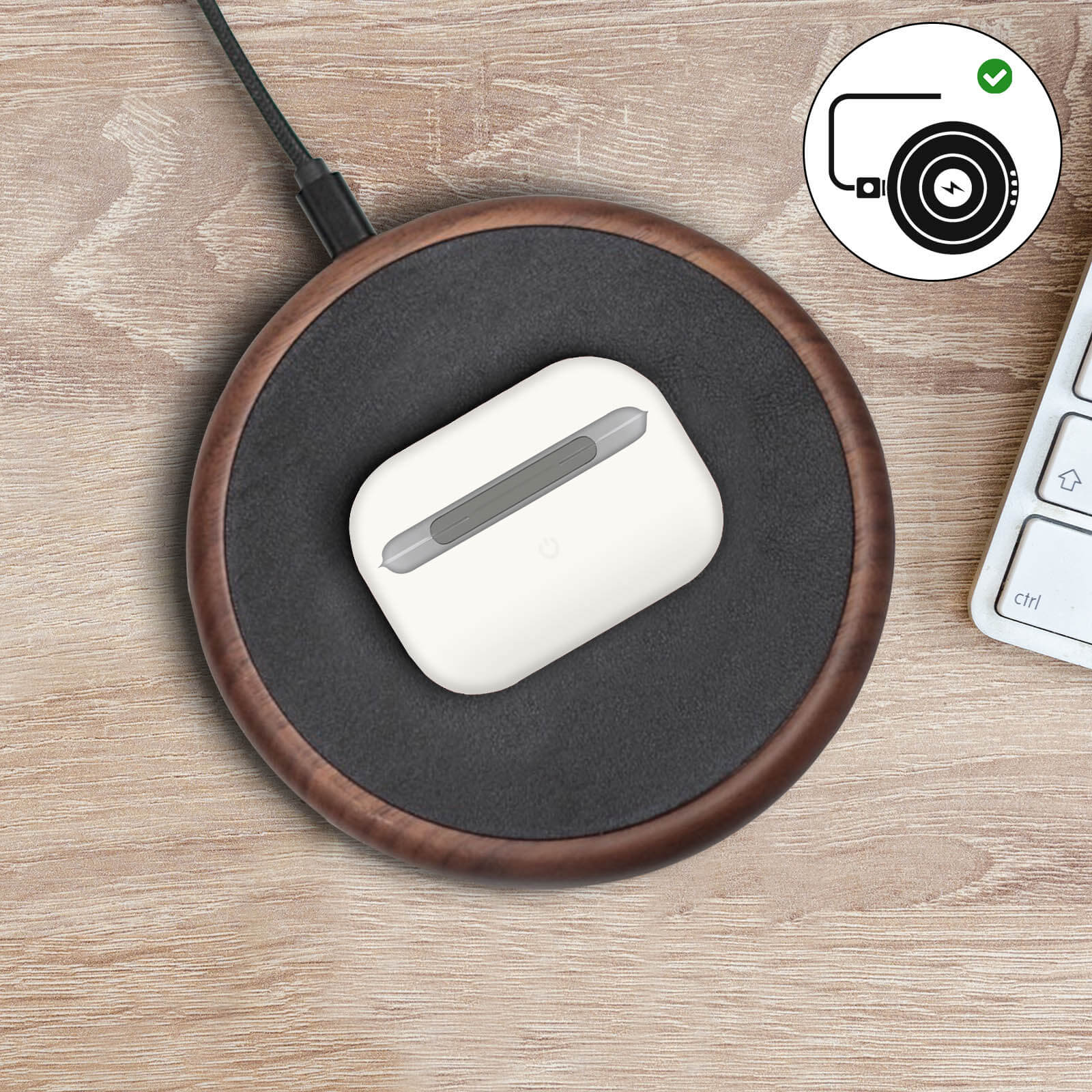 Estuche de carga blanco sobre un cargador inalámbrico de madera, con un cable negro.