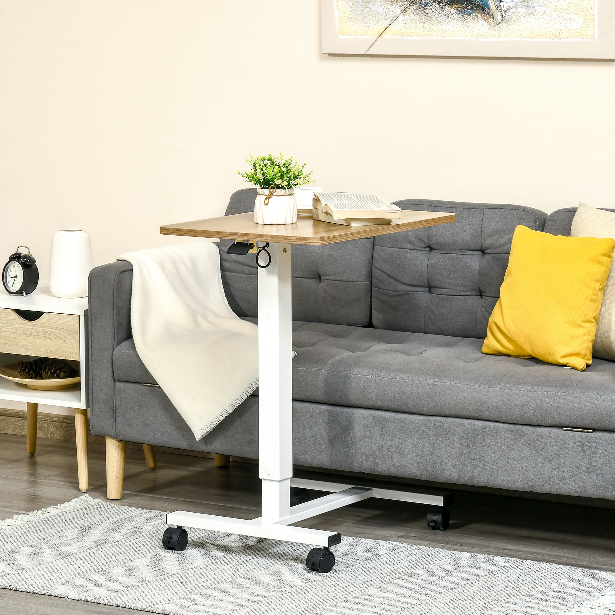 Rollender Tisch mit Holzplatte, Buch und Pflanze darauf, in der Nähe eines Sofas. Grauer Teppich und Wand.